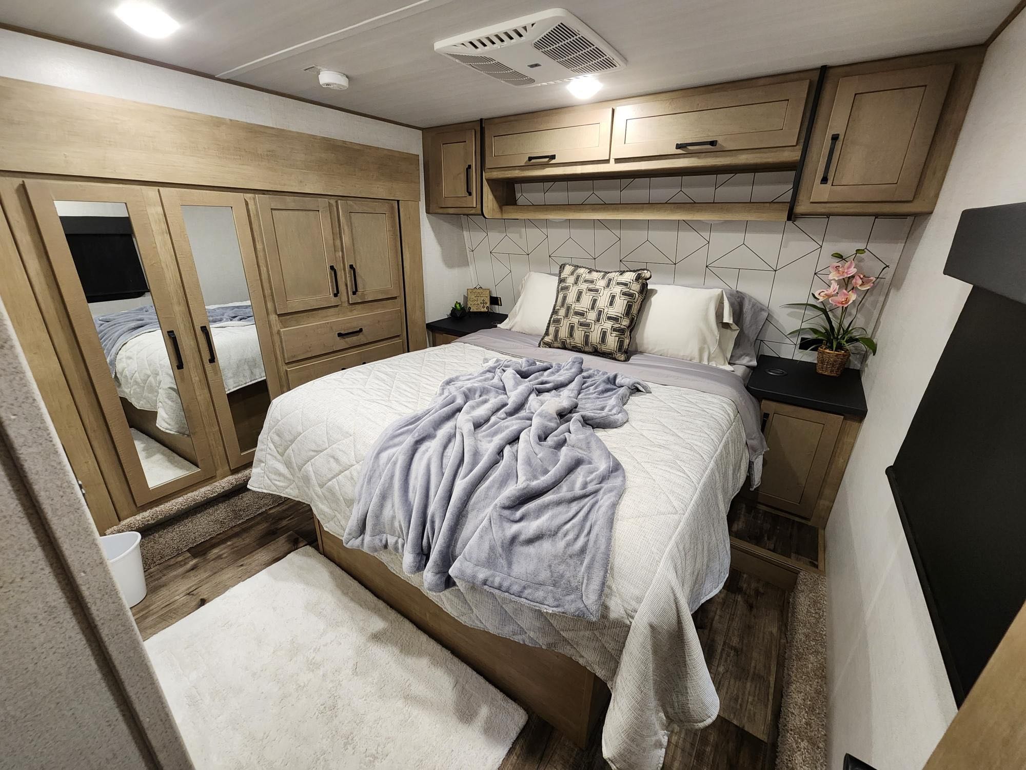 Cozy RV rental bedroom with a comfy queen bed, mirrored wardrobe, ample storage, and stylish decor.. Keystone Carbon 2023