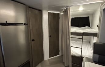 Experience an RV rental! Interior view of bunk beds with privacy curtain, fridge, and storage doors for cozy living.. Forest River Salem Cruise Lite 2022