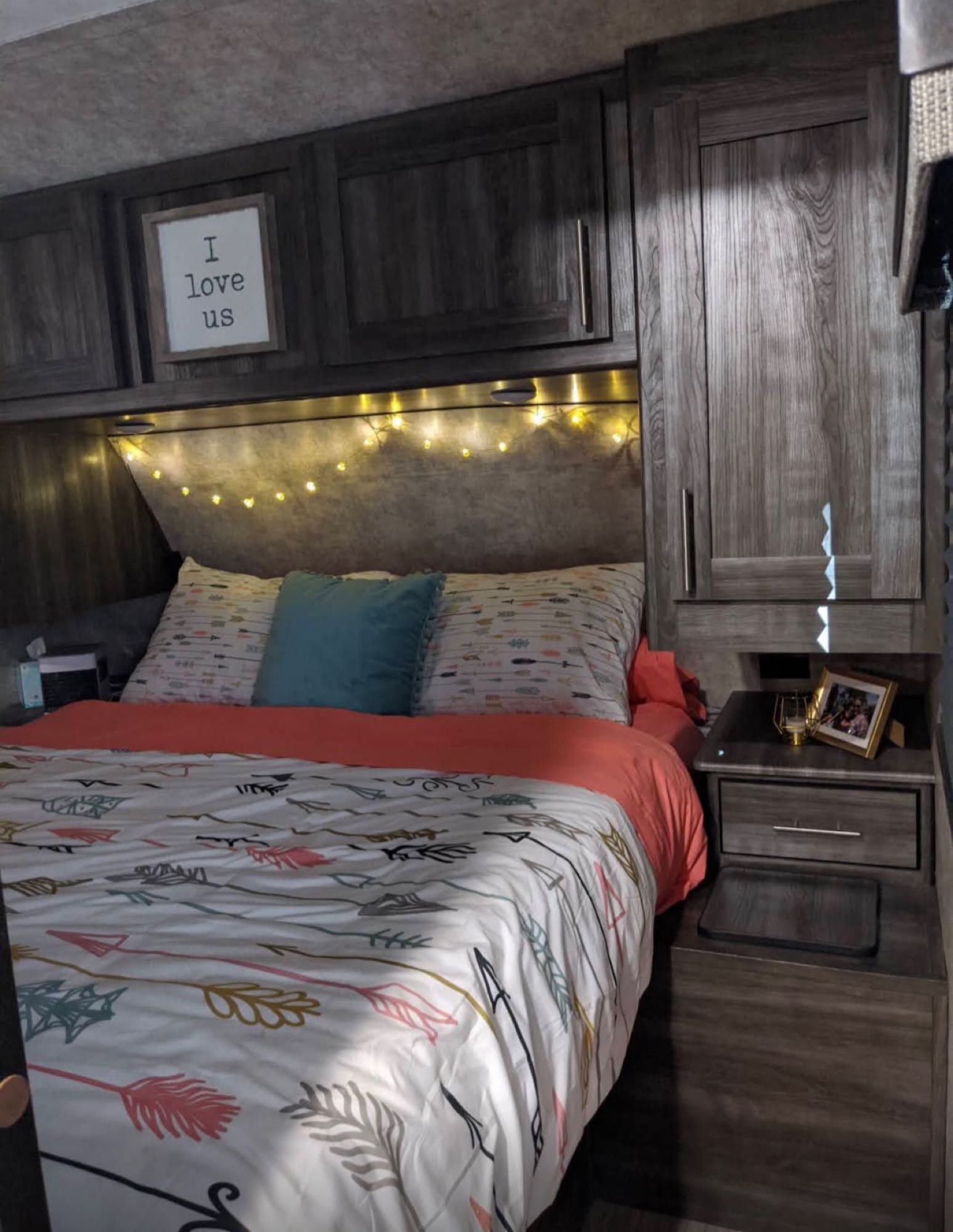 Cozy RV rental bedroom featuring decorative string lights, arrow-patterned bedding, and a sweet 'I love us' sign.. Highland Ridge RV Open Range Ultra Lite 2019