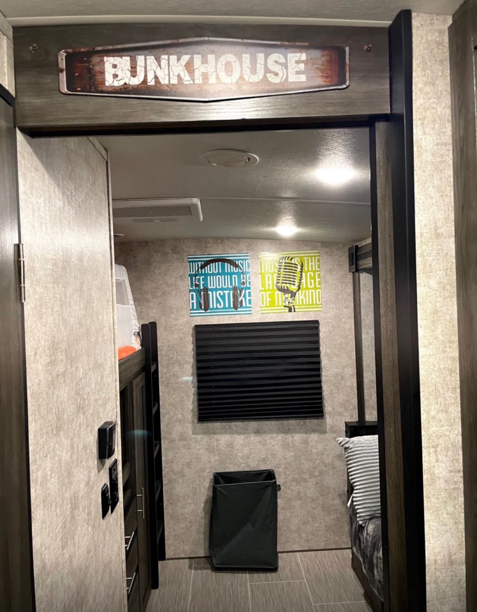 Step into this RV rental's cozy bunkhouse with a "BUNK HOUSE" sign, featuring comfy bunk beds, storage, and music-themed decor.. Highland Ridge RV Open Range Ultra Lite 2019