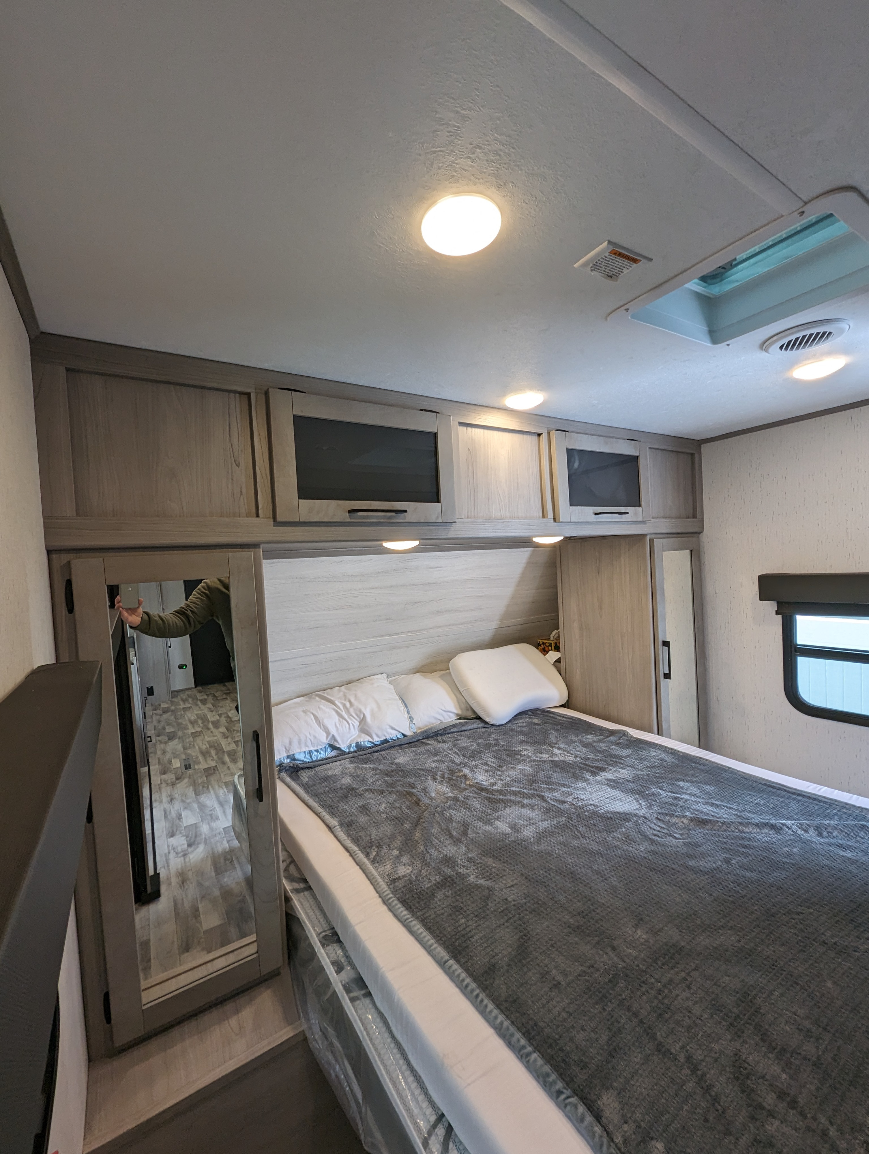 Spacious RV rental bedroom with light wood cabinetry, a mirrored closet, comfortable bed, and overhead lighting.. Dutchmen Kodiak Ultra Lite 2023