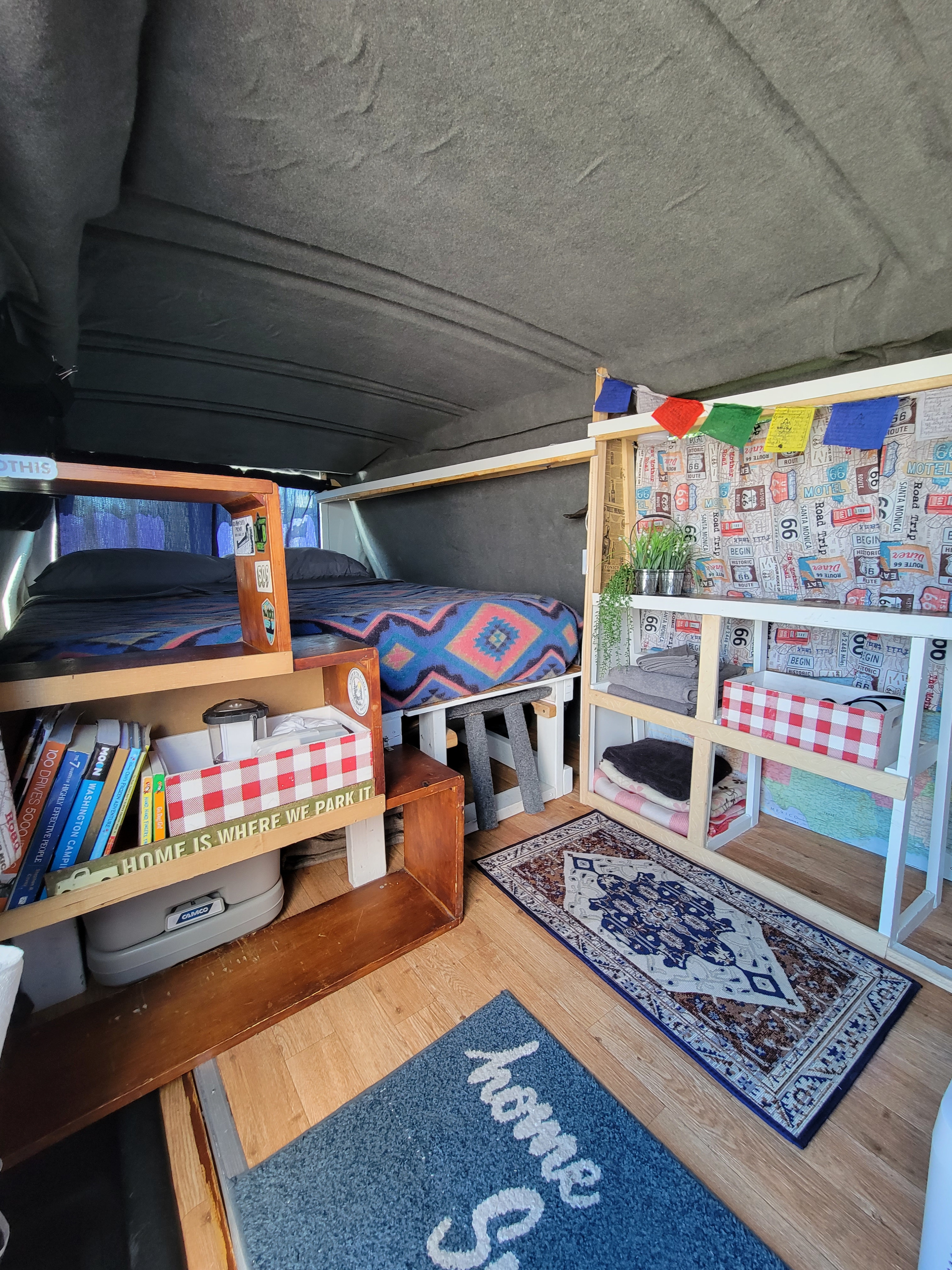 Cozy **RV rental** interior, showing a neat bed, organized shelving, and a **portable toilet**. It's a well-equipped **camper van** space.. Chevrolet 3500 Express 2016