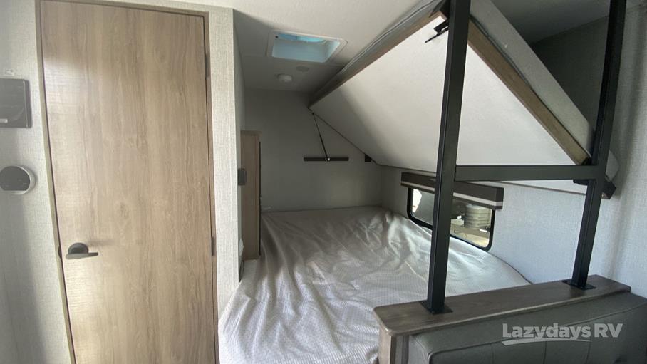 This rv rental interior shows a sleeping area with a lower bed and a folded-up upper bunk, maximizing space in this camper.. Grand Design 2023