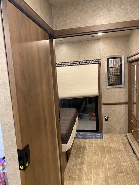 View into a modern RV rental bedroom, featuring a bed, wood flooring, and built-in storage. Ideal for travel.. Thor Outlaw 2022