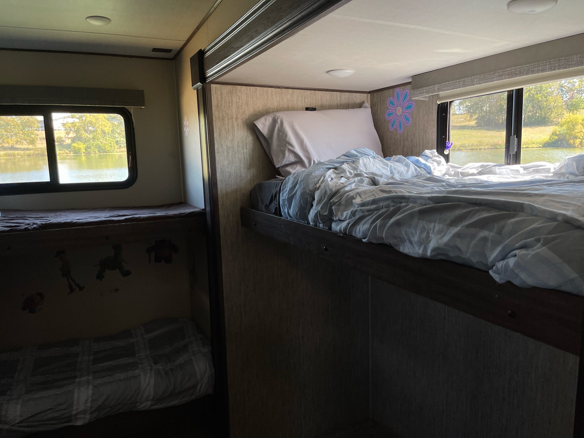 Inside an RV rental: A bunkhouse with two beds and large windows offering scenic lake views. Ideal for family adventures.. Grand Design Solitude 2019
