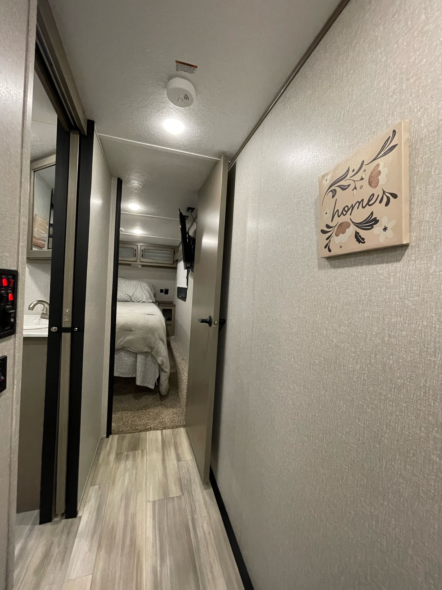 RV rental interior: A bright hallway leads to a cozy bedroom with modern design, offering comfort in a compact space.. Coachmen Chaparral 2021