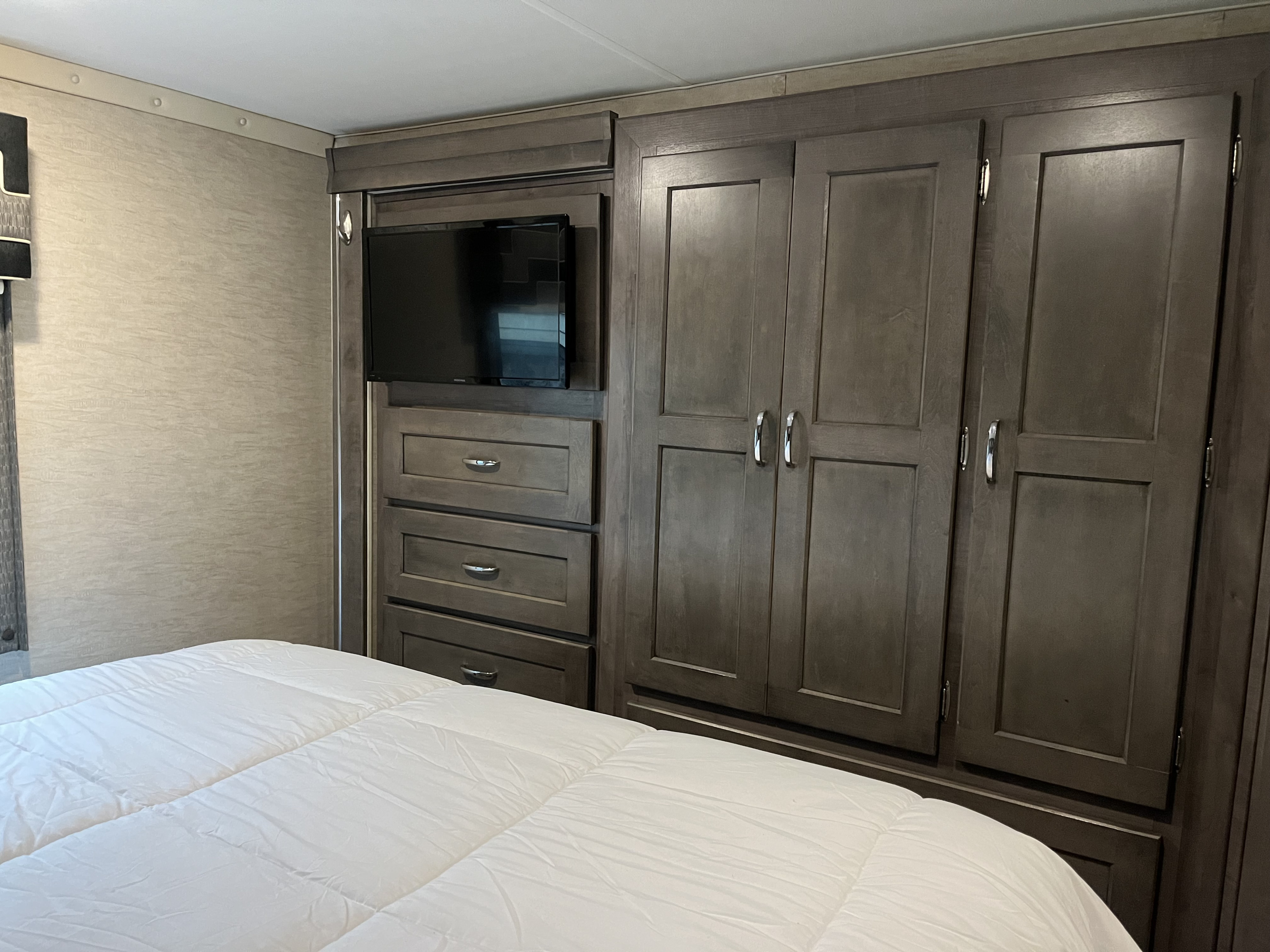 Inside an RV rental bedroom: functional design with built-in TV, drawers, and wardrobe storage for comfortable travel.. Winnebago Spirit 2017
