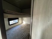 RV rental interior: A cozy bunk bed area with an upper bunk, lower bunk, and window, ideal for travel comfort.. Dutchmen Coleman Lantern LT 2023