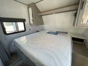 This RV rental features a clean, modern bedroom with a comfortable bed and overhead storage, ideal for your travels.. Dutchmen Coleman Lantern LT 2023
