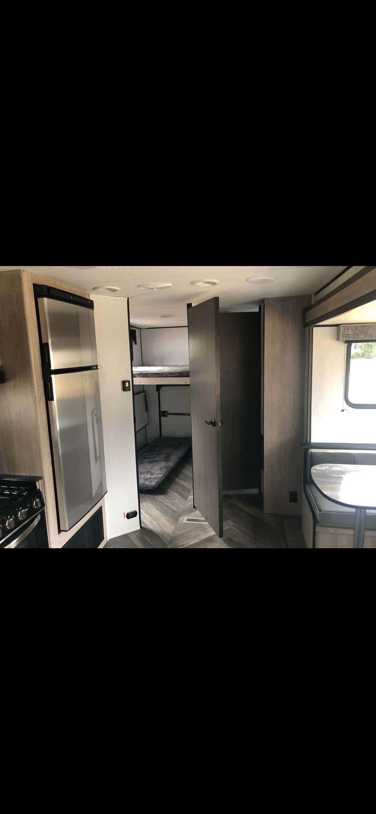 RV rental interior: kitchen with fridge/stove, bunk beds, and dinette seating. Bright, modern travel trailer setup.. Heartland Prowler 2022