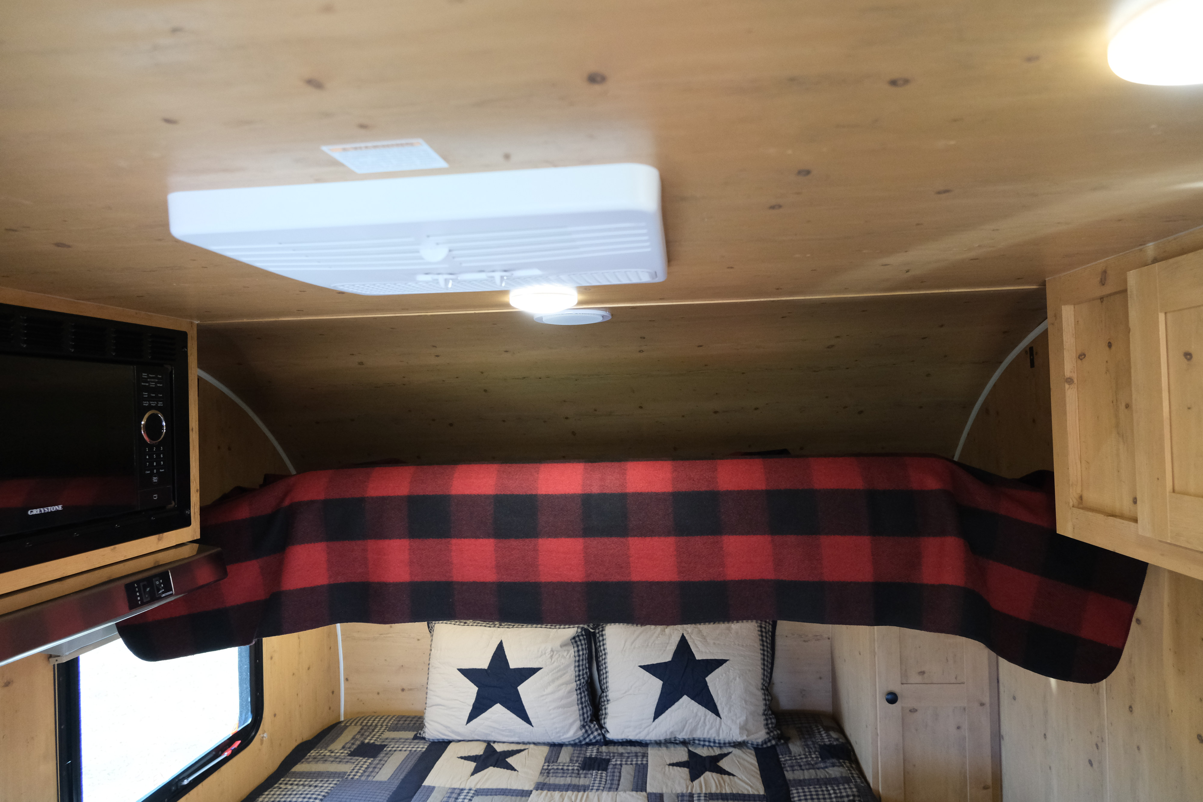 Cozy RV rental interior: bed with plaid blanket, microwave & wood accents.. Sunray Sunlite 16BH 2023