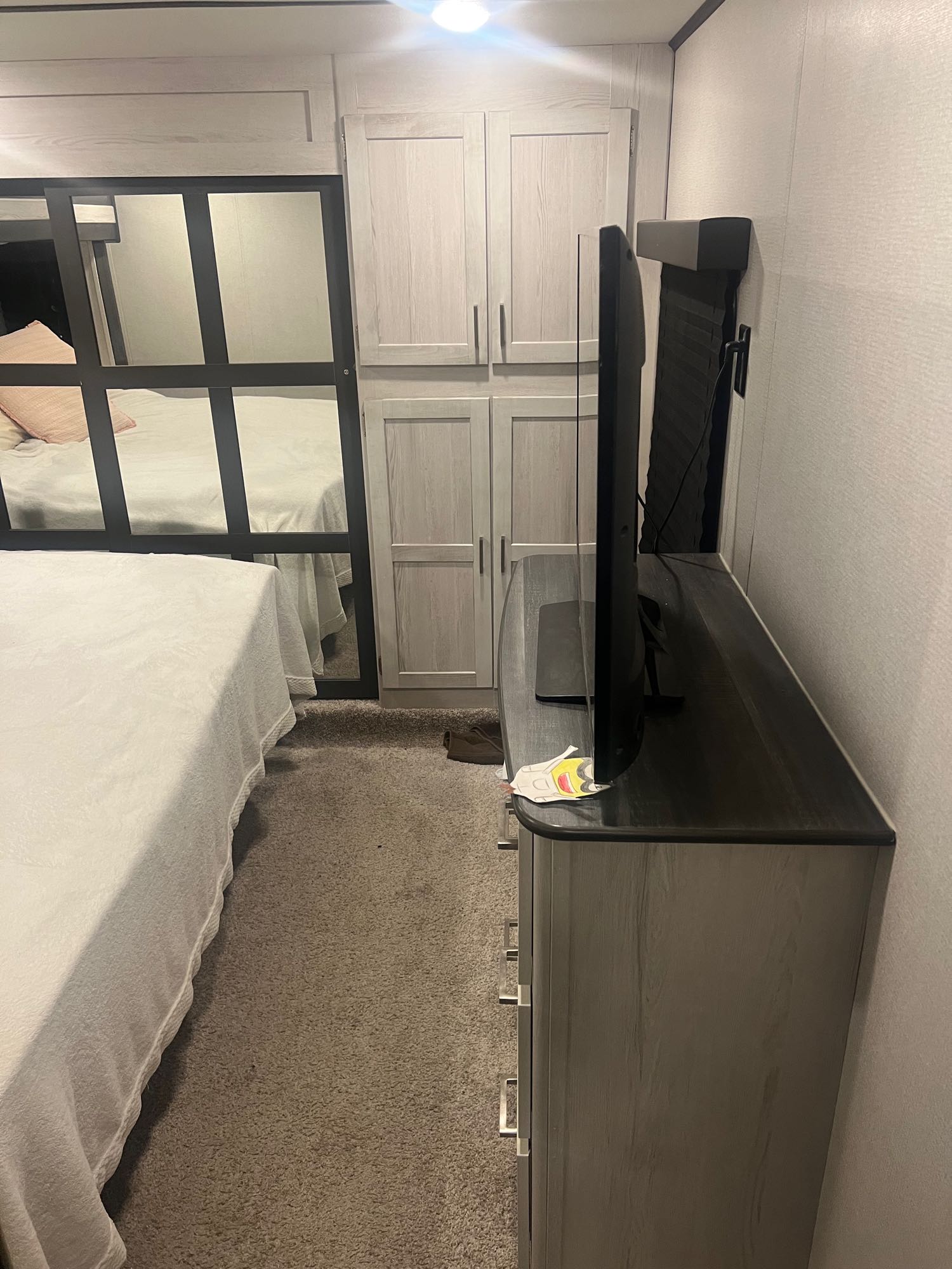 Inside an RV rental, this cozy bedroom features a bed, mirrored closet, built-in storage, and a TV on a dresser, maximizing space.. Keystone RV Sprinter Limited 2022