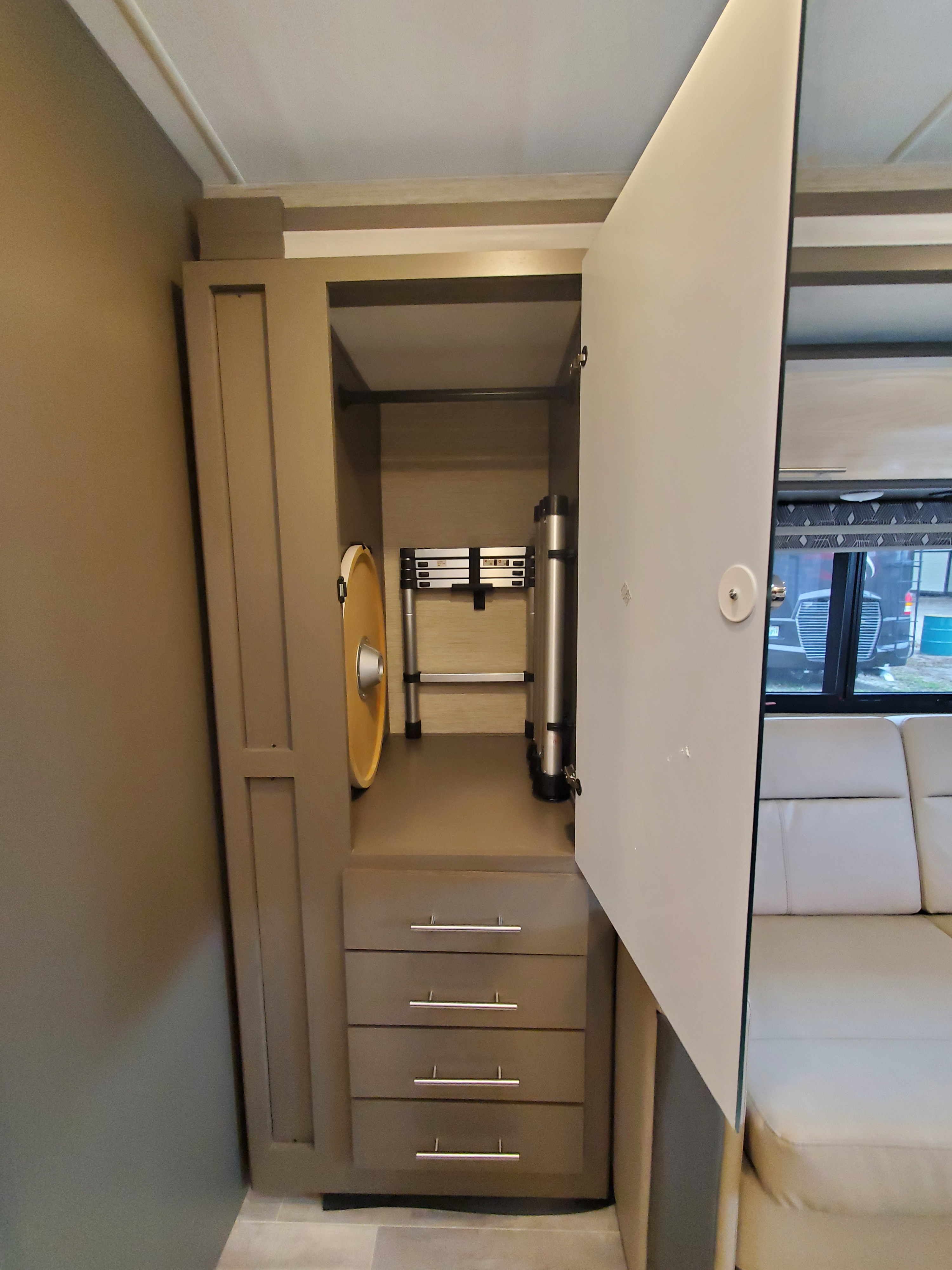 This rv rental closet provides compact storage with a folding ladder, round table, and drawers.. Thor Motor Coach Axis 2023