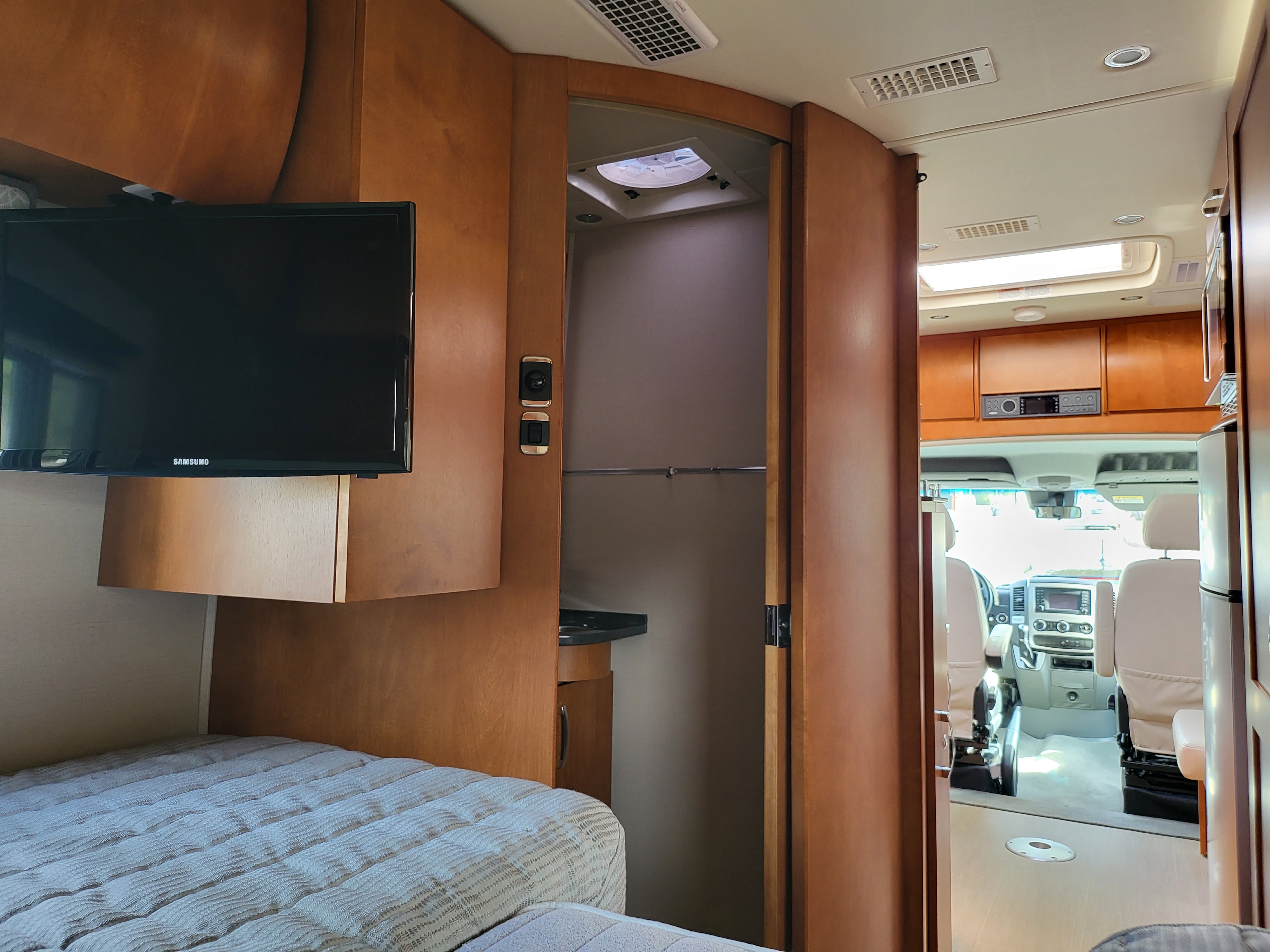 Experience an rv rental's interior: bed, compact bath, and driver's cabin visible from rear. Ready for travel!. Leisure Travel Unity Twin Bed 2017