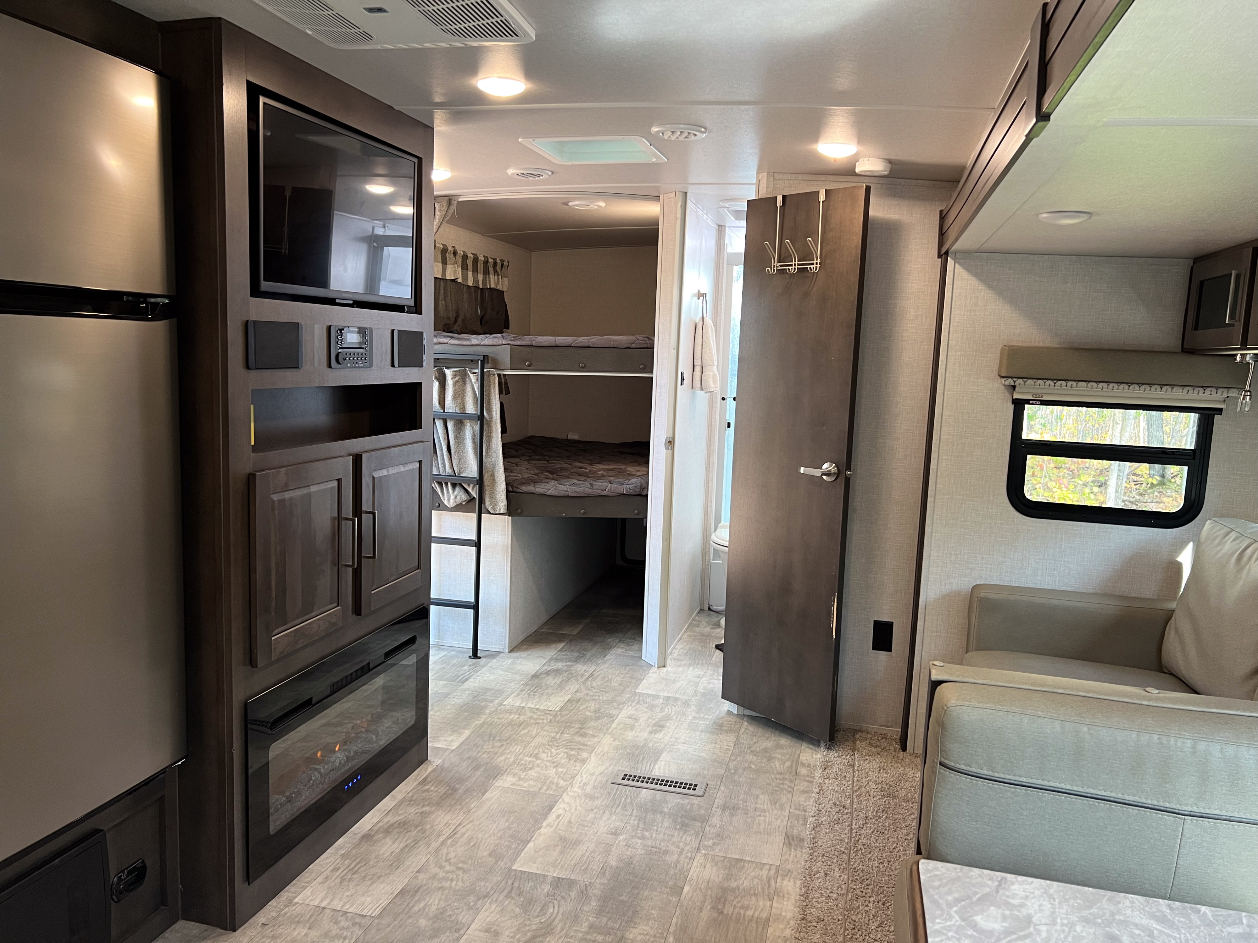An RV rental's inviting interior features a fridge, TV, fireplace, bunk beds, bath, and sofa in the living area.. Forest River Flagstaff Super Lite 2021
