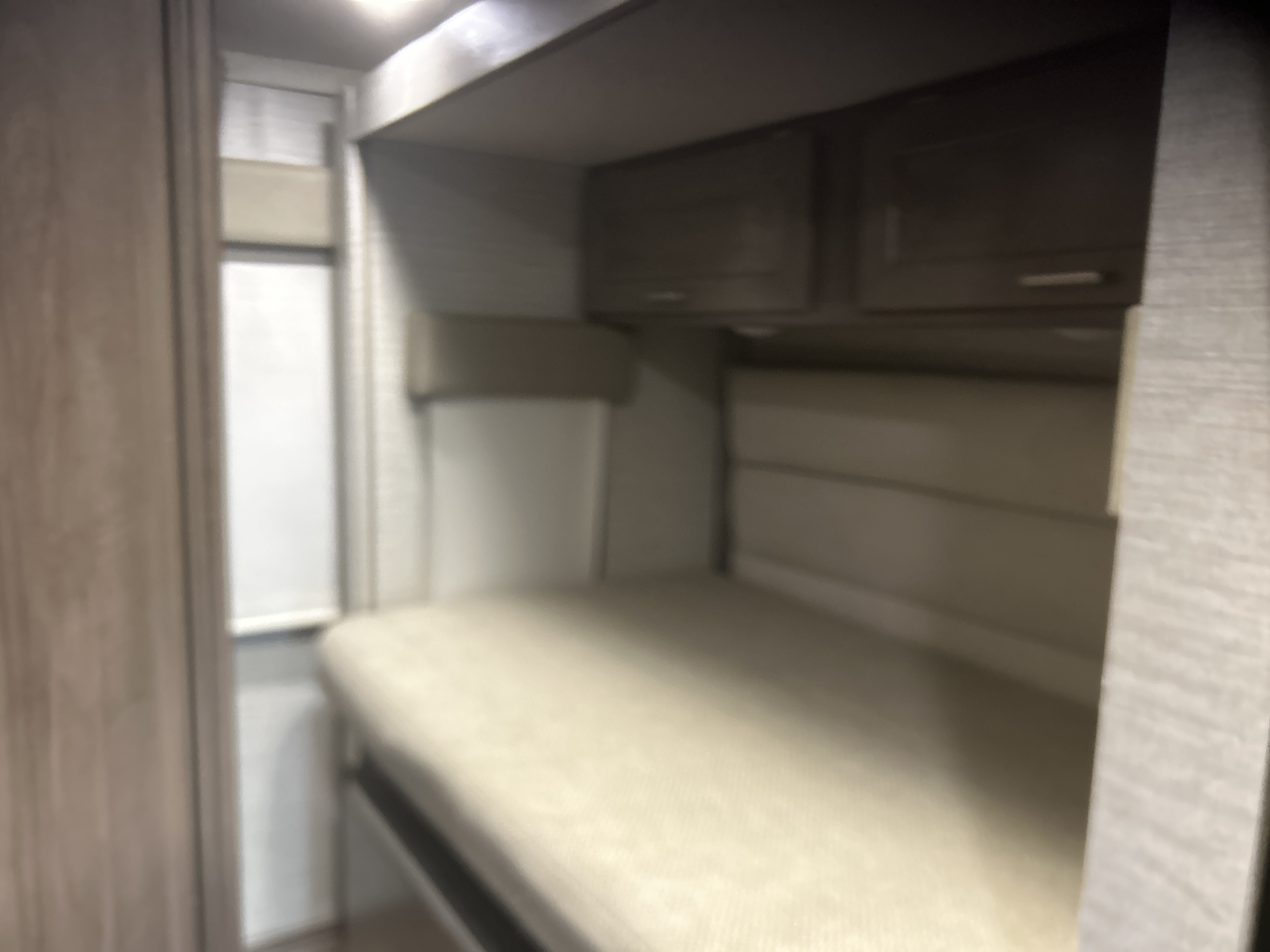 RV rental interior features a compact sleeping area with a bed and overhead cabinets.. Winnebago Minnie Winnie 2020