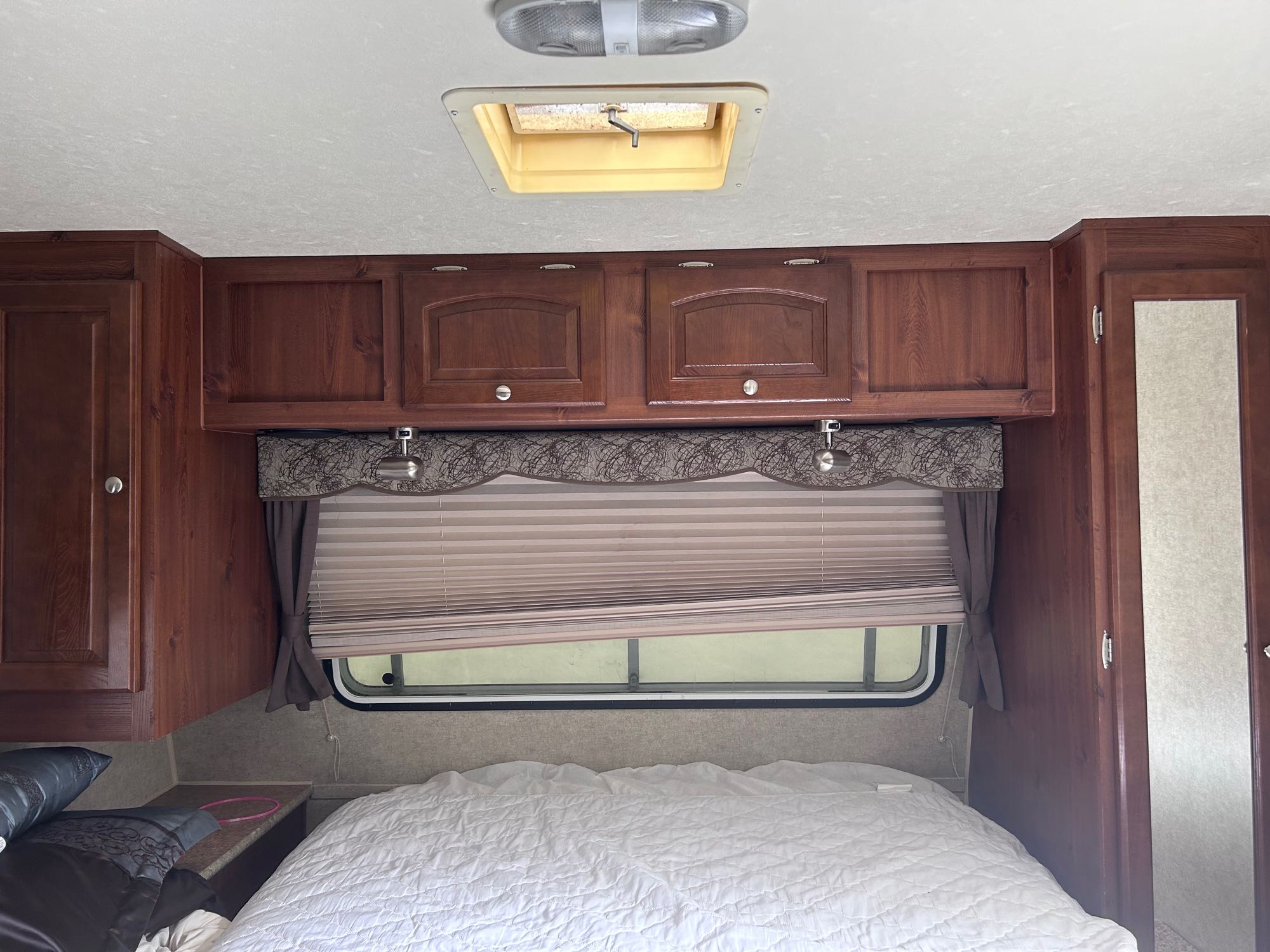 RV rental bedroom with spacious wood cabinets, a comfortable bed, and overhead light/vent. Ready for your trip!. Forest River Rockwood Mini Lite 2013
