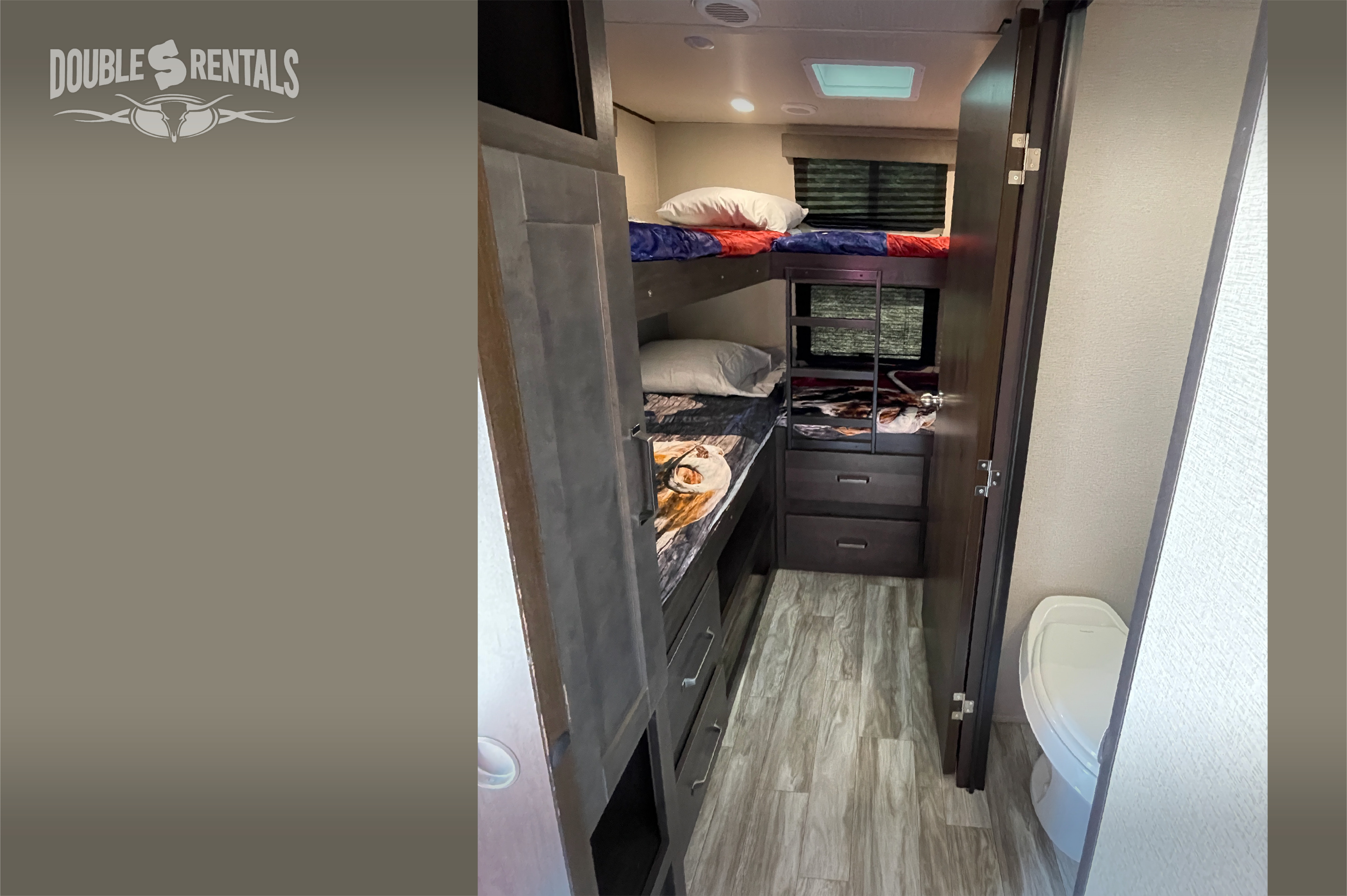 RV rental interior: cozy bunk beds with ladder, built-in storage, and a compact toilet area. Ideal for family adventures.. Grand Design Transcend 2022