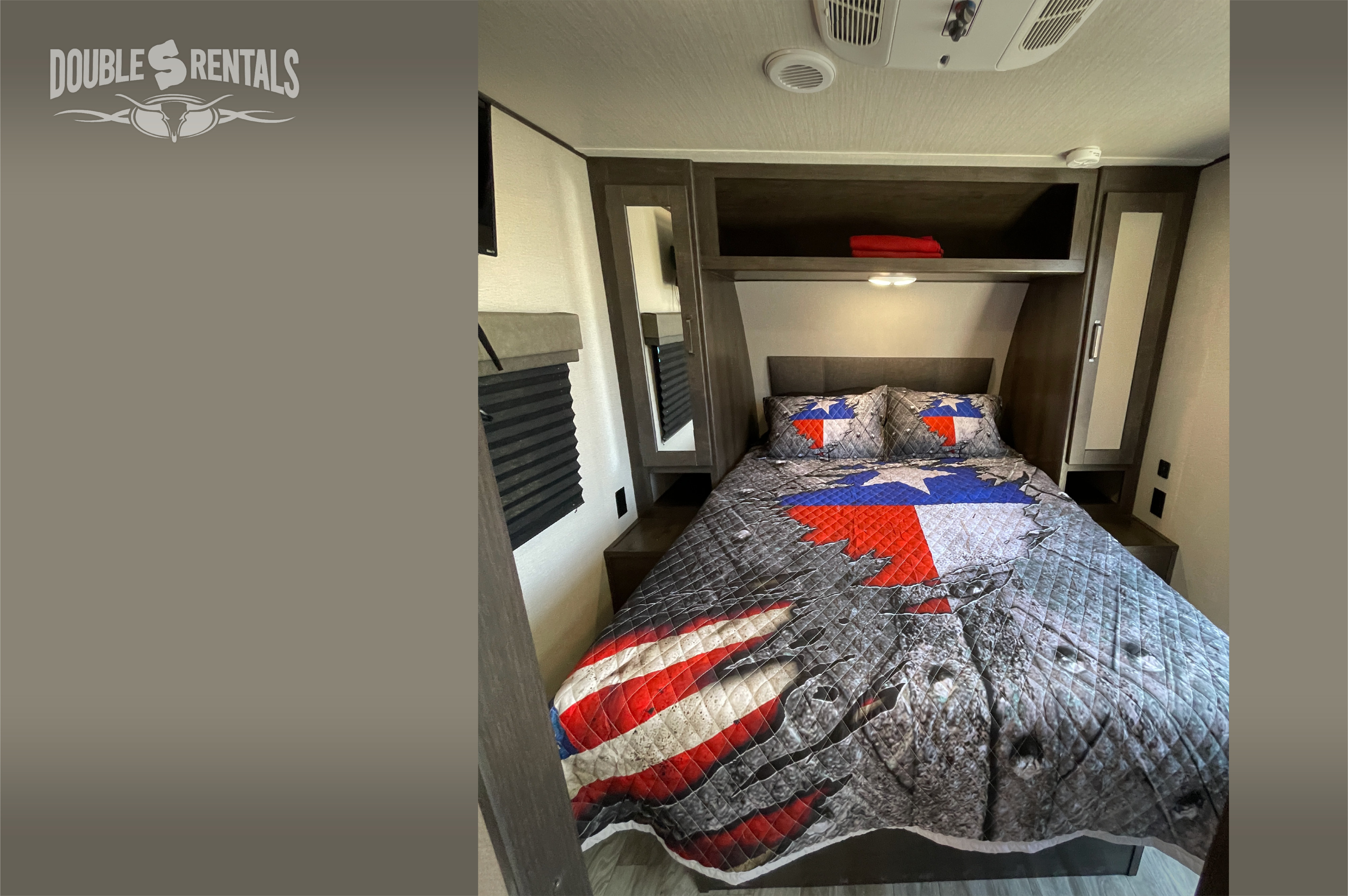 Cozy RV rental bedroom featuring a patriotic Texas flag and American flag quilt, with convenient overhead storage.. Grand Design Transcend 2022