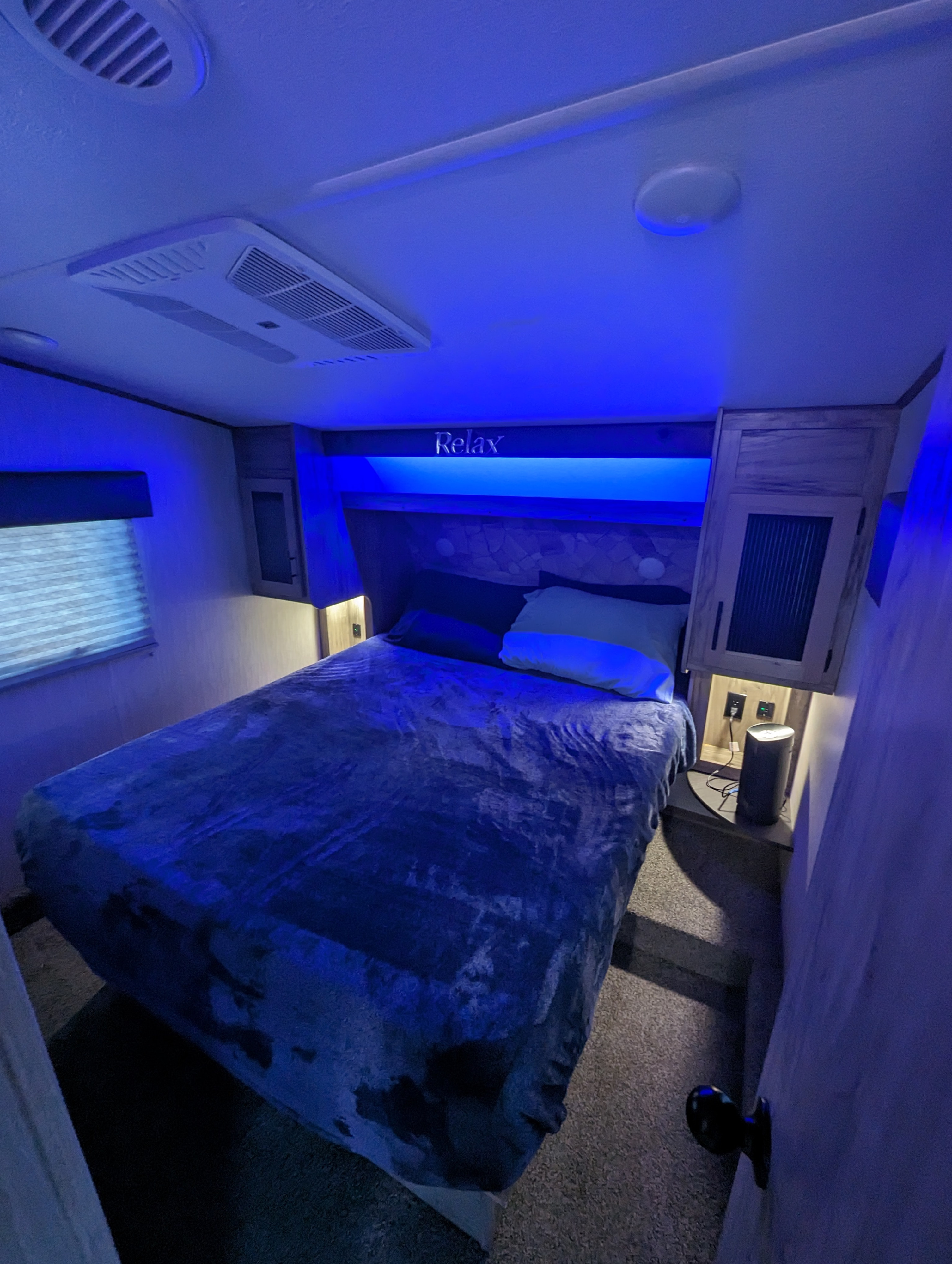 Relax in this cozy RV rental bedroom, featuring blue mood lighting and comfortable amenities for a perfect night's rest.. Forest River Cherokee Arctic Wolf 2021