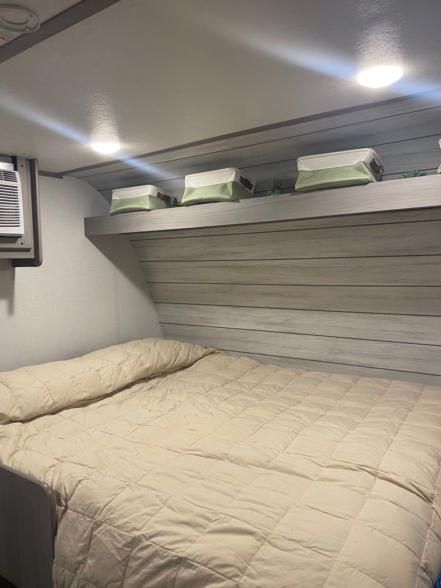 This RV rental's compact bedroom offers a comfy bed, overhead storage bins, built-in lights, and an AC unit.. Dutchmen Coleman Lantern LT 2023