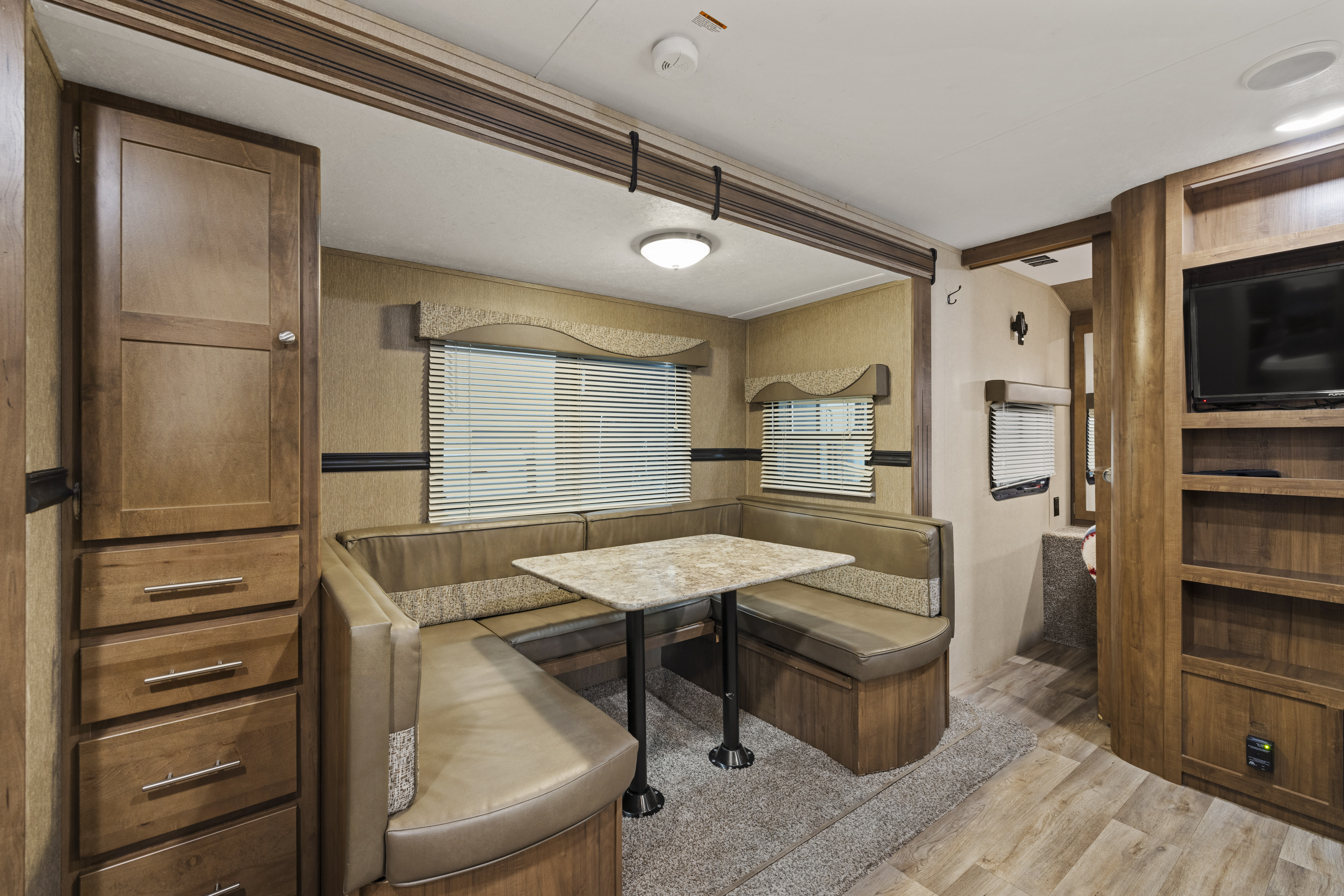 RV rental interior features a comfortable dinette, wood cabinets, and built-in entertainment area for travel.. Aspen Trail Dutchman 2017