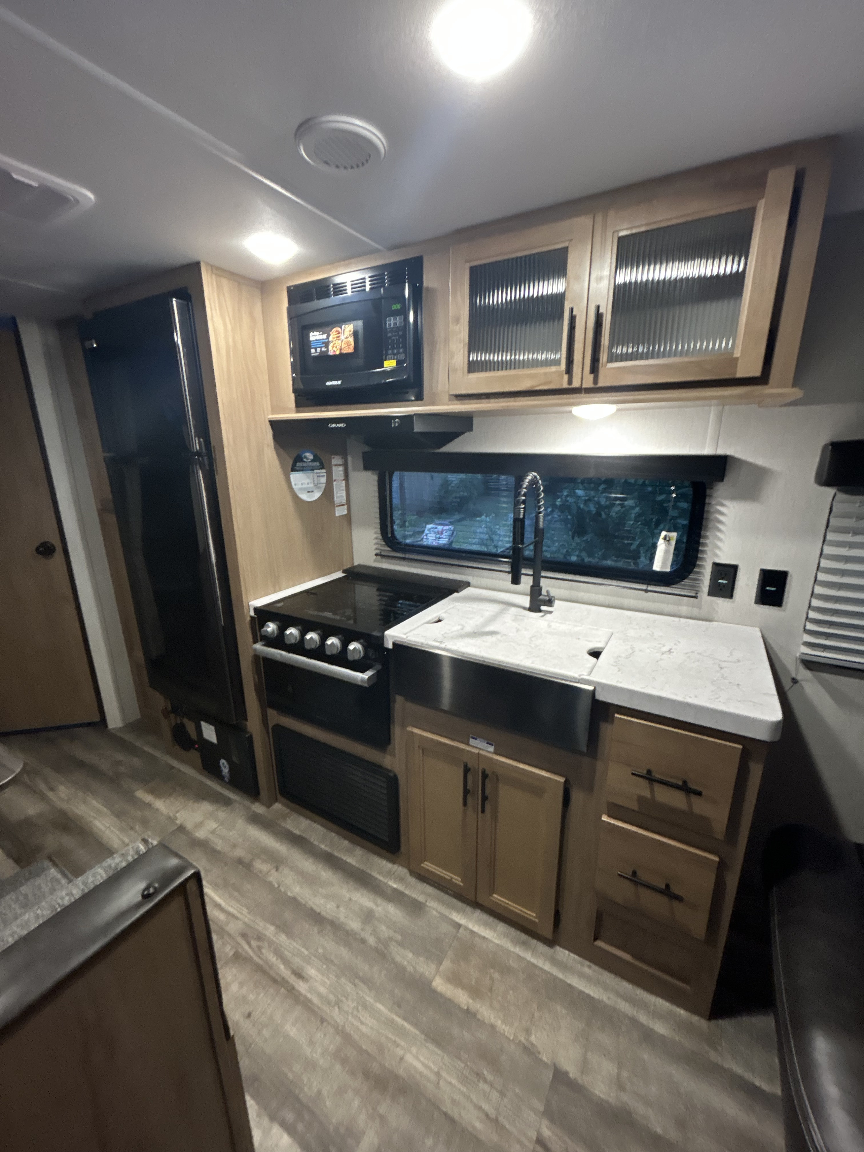 Explore this well-equipped RV rental kitchen featuring a fridge, microwave, stove, and farmhouse sink. Ideal for your next camper adventure.. Forest River Cherokee Grey Wolf Special Edition 2023