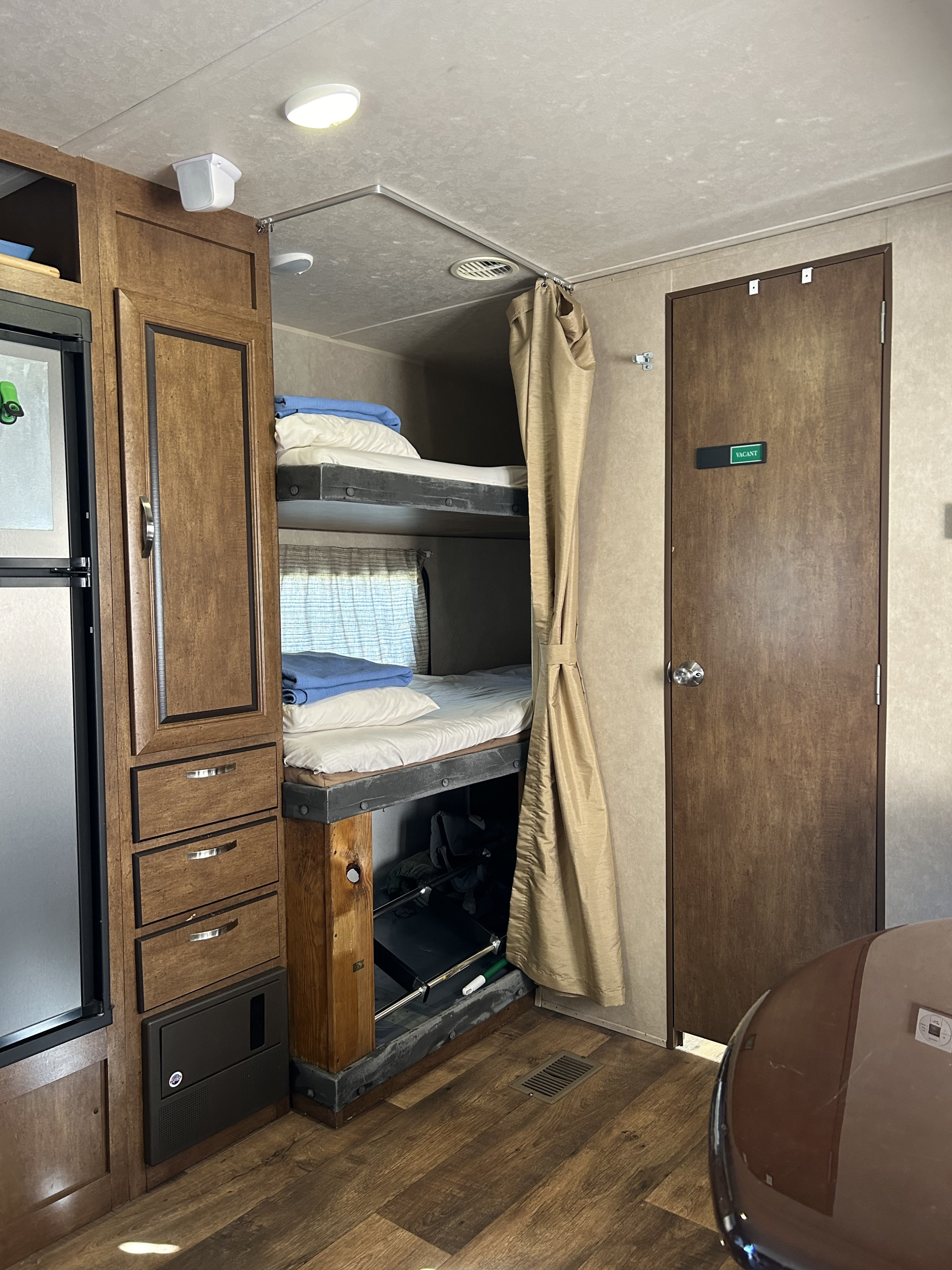 RV rental interior featuring cozy bunk beds, a compact kitchen area, and a bathroom door within the camper.. Forest River Salem 2017