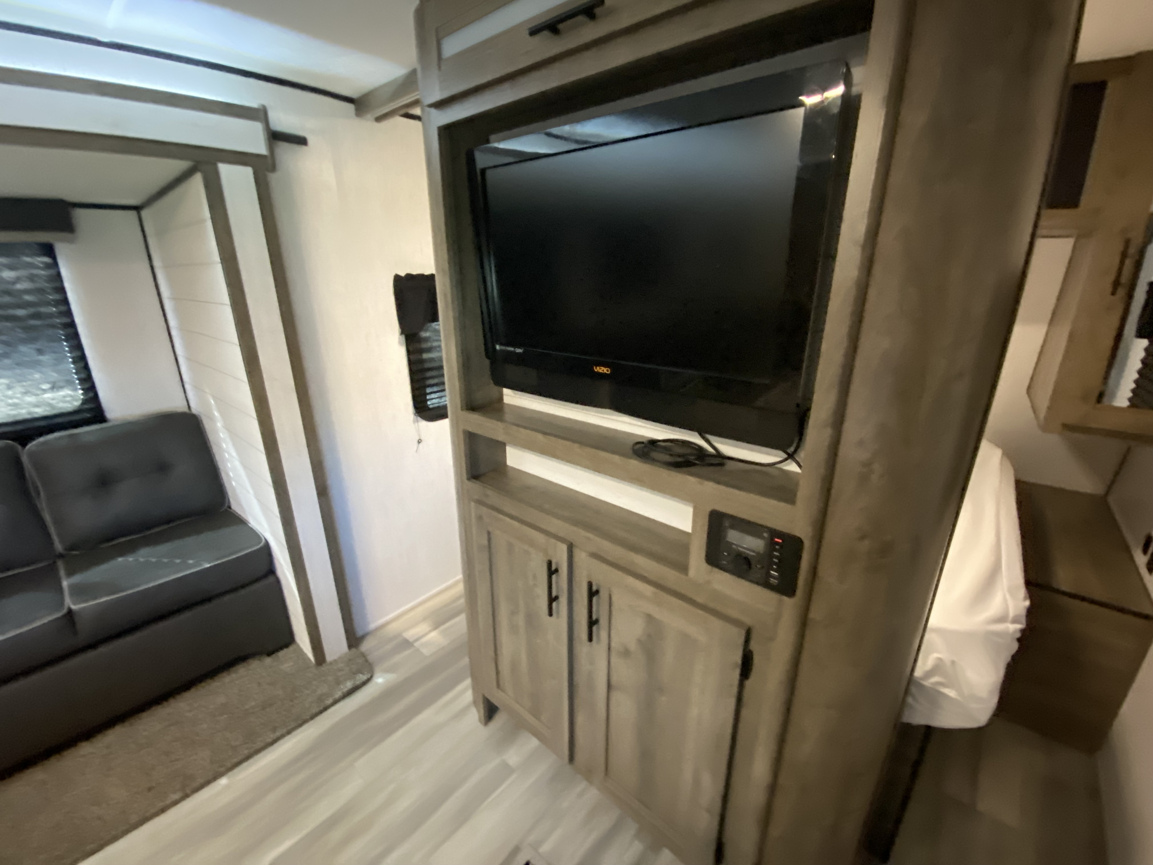 RV rental interior featuring a cozy living area with a dark sofa, modern entertainment center, and a glimpse of the bedroom.. Heartland Pioneer 2021