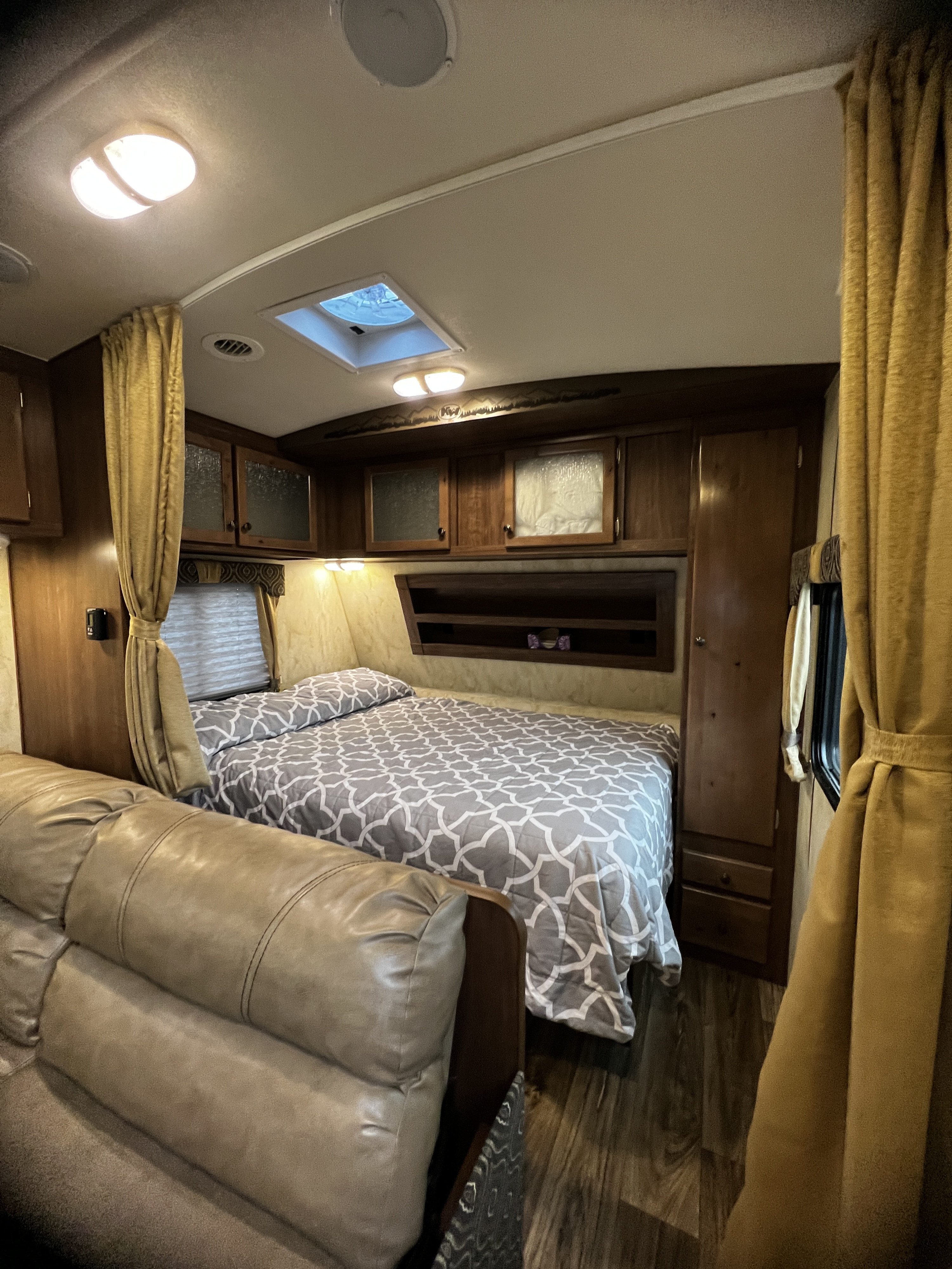 RV rental bedroom and living area, showcasing a comfy bed, leather sofa, and ample storage for your travels.. Nash 22H 2021