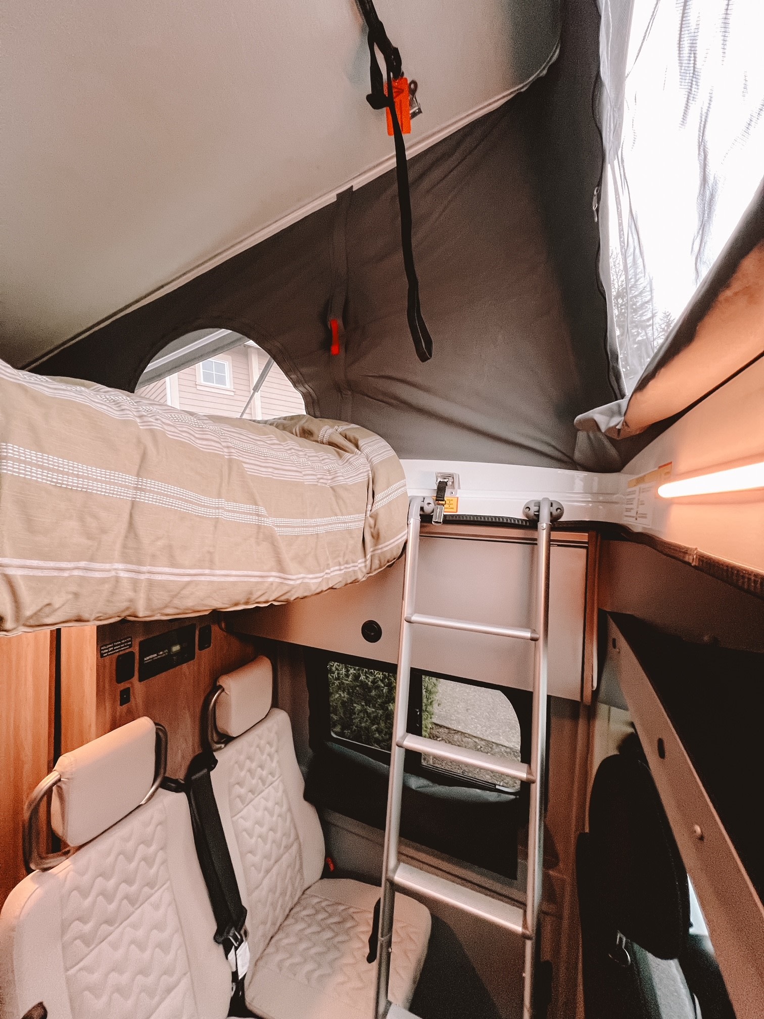 Step inside this RV rental featuring a cozy pop-top loft bed with ladder, passenger seats, and controls. Adventure awaits!. Winnebago Solis 59PX 2023