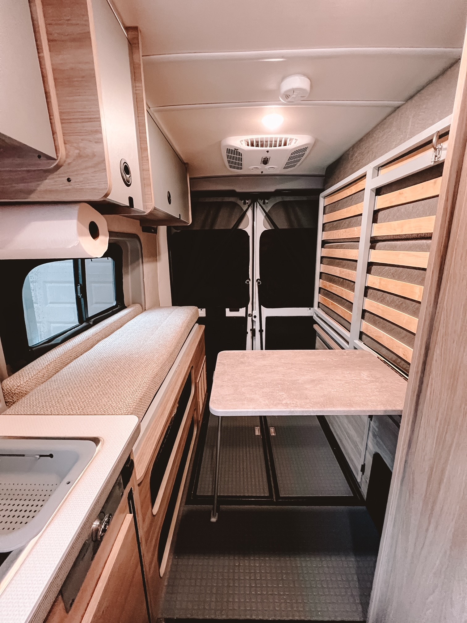 Explore this **rv rental**'s cozy interior, featuring a compact kitchenette, a plush bench/bed, and a portable dining table.. Winnebago Solis 59PX 2023