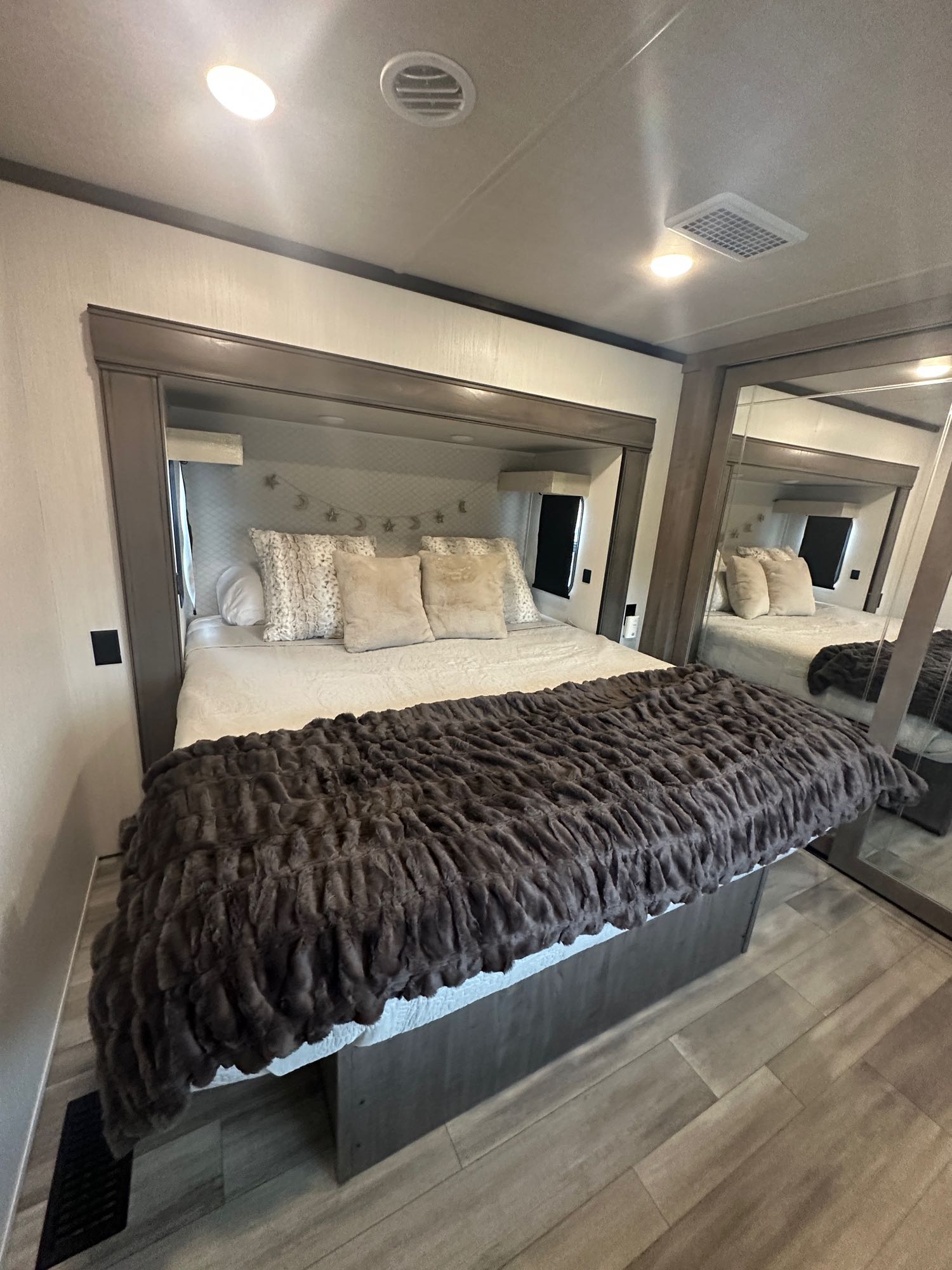 Cozy RV rental bedroom with a large bed, fluffy blankets, and mirrored closets. Ideal for travel comfort and relaxation.. Cedar Creek Cedar Creek Fifth Wheel 2022