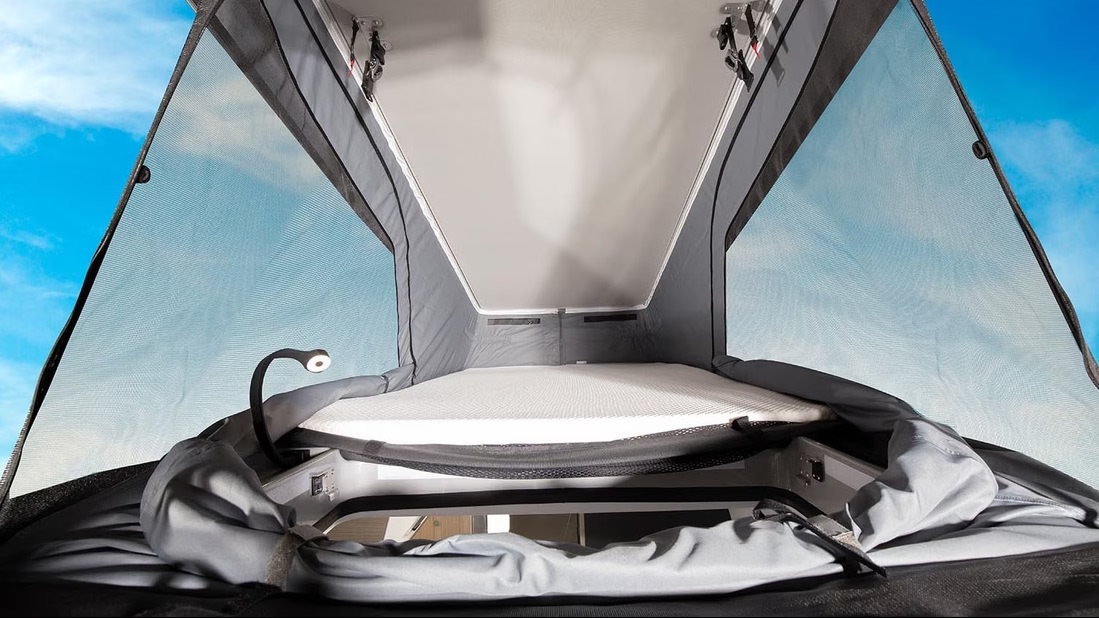RV rental pop-top bed: Cozy sleeping area with flexible reading lamp, storage, and mesh windows viewing the sky.. SUN LIVING SP 60 AVEC TENTE DE TOÎT 2024