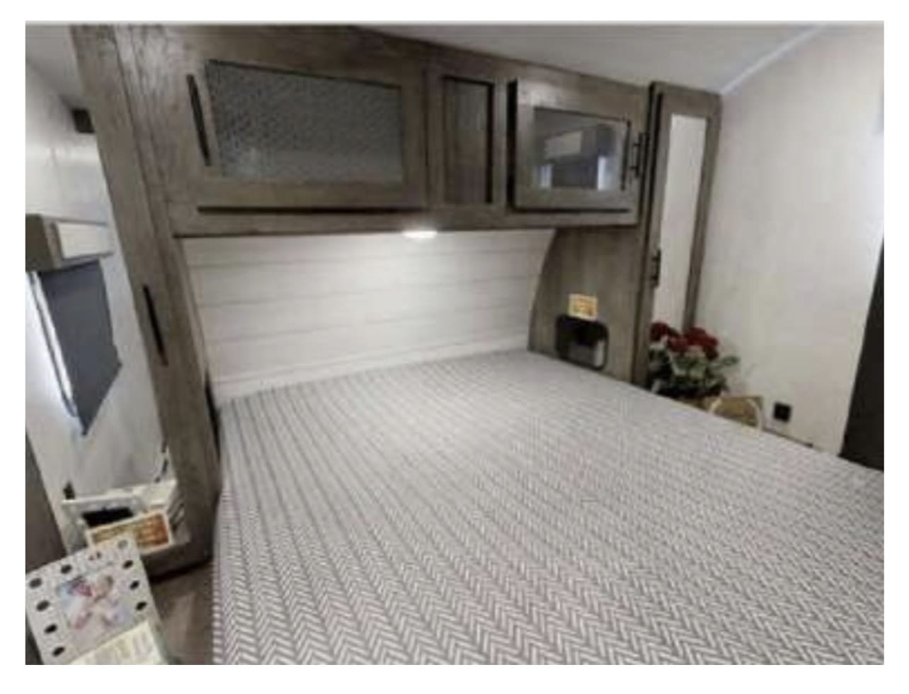 Cozy RV rental bedroom: modern wood cabinets, comfortable bed with herringbone pattern. Perfect for your next adventure.. Forest River Salem 26 DBUD 2023