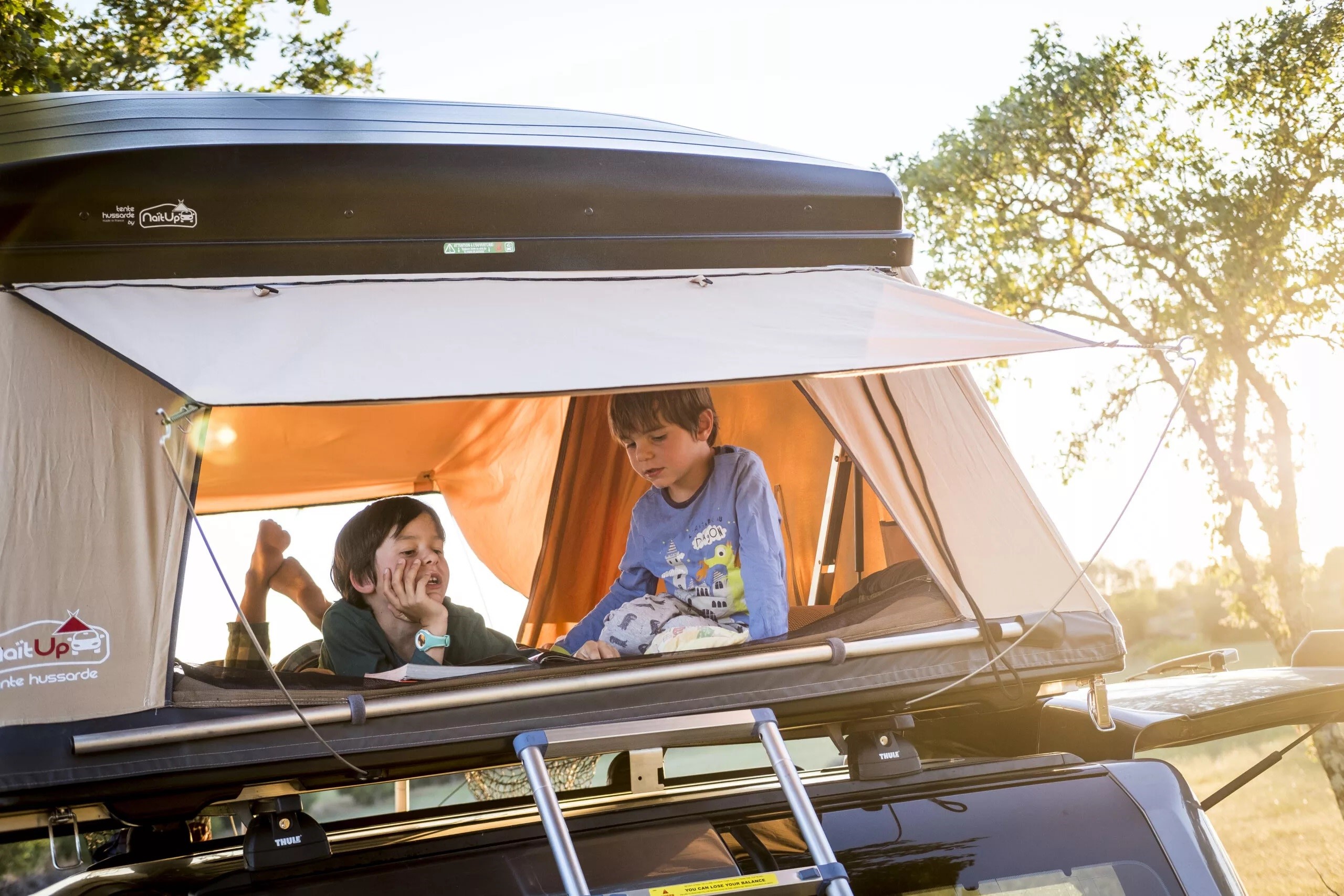 Kids enjoying a NaitUp "tente hussarde" rooftop tent, a perfect feature for an RV rental camping trip.. NaïtUp Hussarde Family 5 personnes 2024