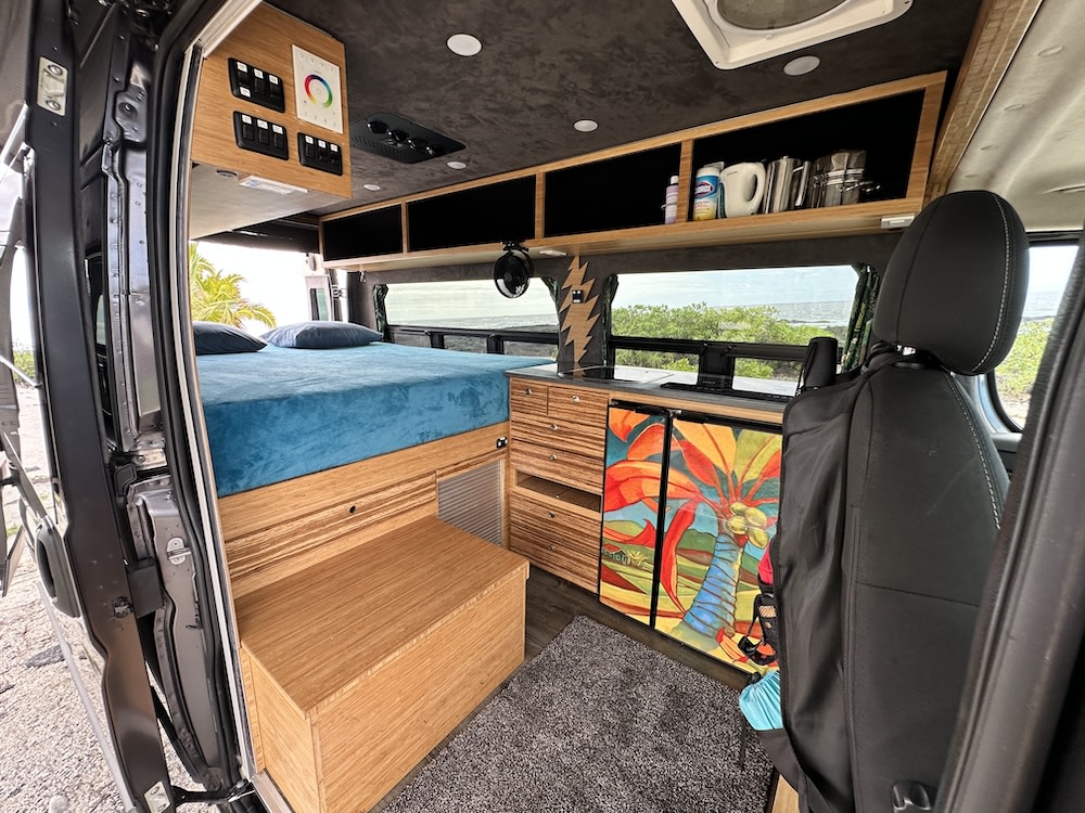 RV rental: custom wood interior features a comfortable bed, compact kitchen, tropical fridge art, and ocean views.. Ram Promaster 2017