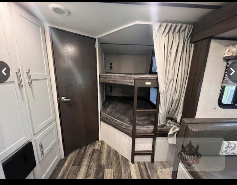 Cozy RV rental interior showcasing bunk beds with ladder, private door, and spacious cabinets. Ideal for family trips.. Keystone RV Bullet Ultra Lite 2019