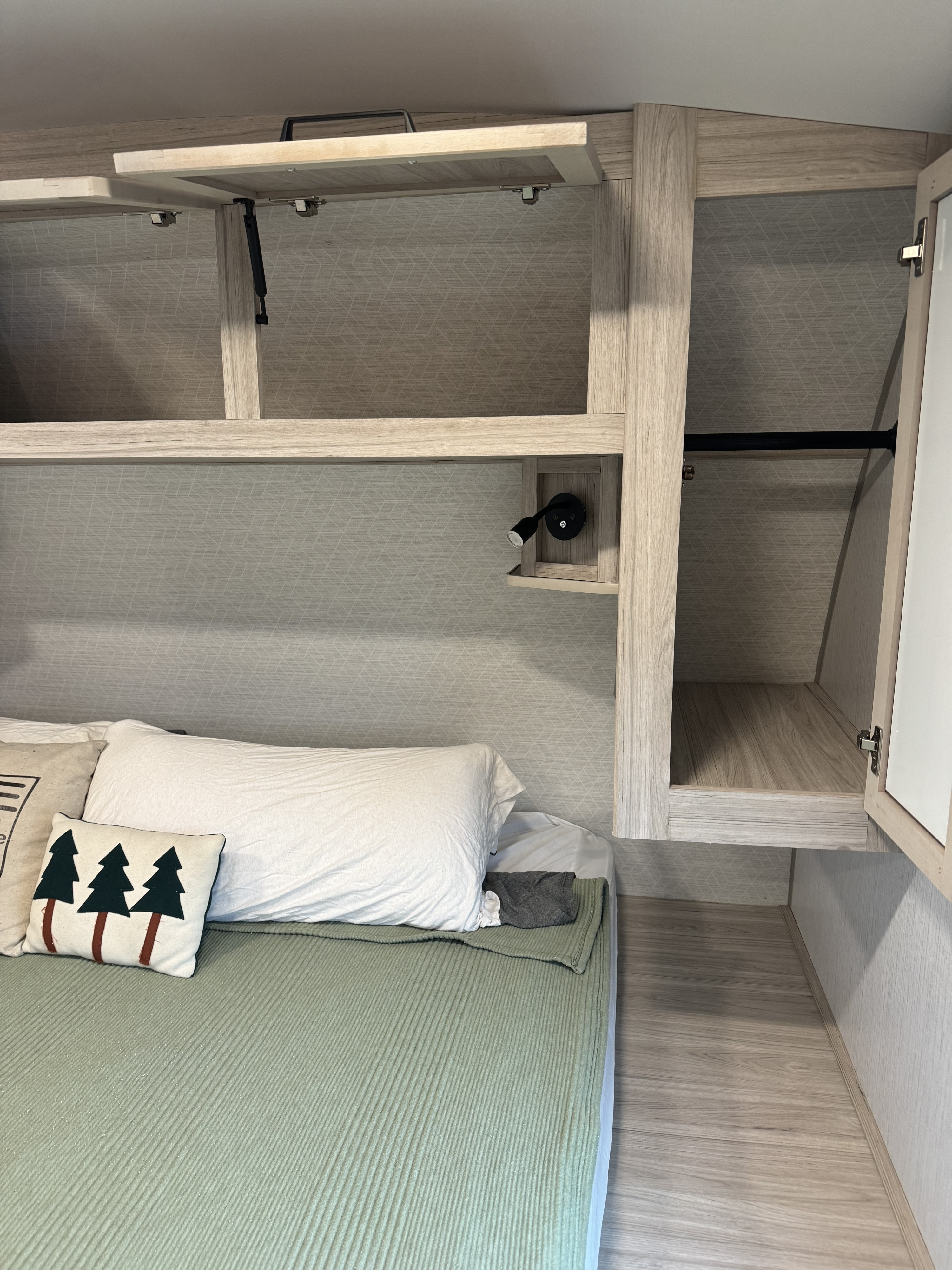 Cozy RV rental bedroom showcasing clever overhead storage, including open cabinets, a reading light, and compact bed area.. Cruiser Twighlight Signature 2023