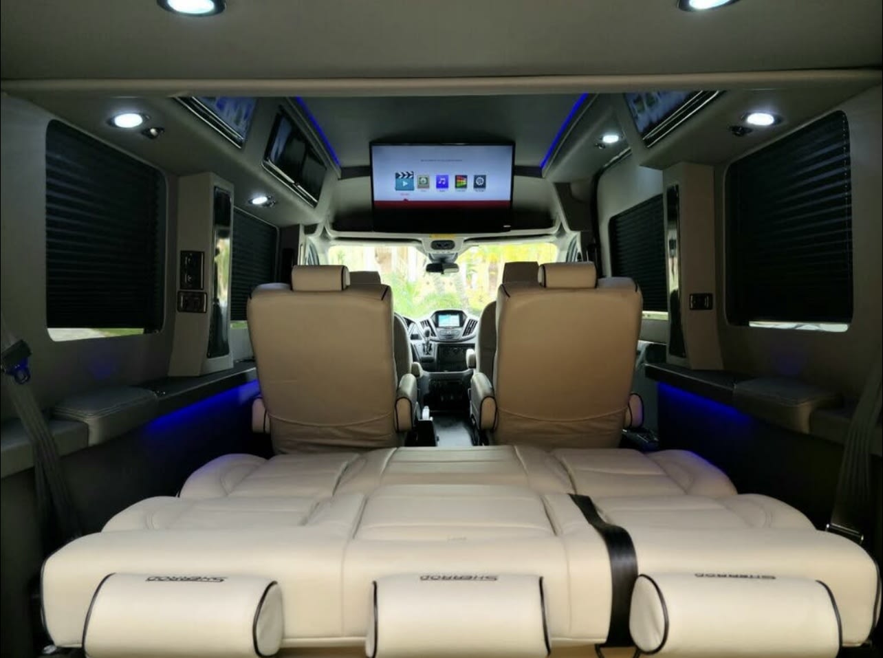 Luxurious RV rental interior with convertible bed, captain's chairs, and entertainment screen for comfortable travel.. Ford Transit Custom 2017