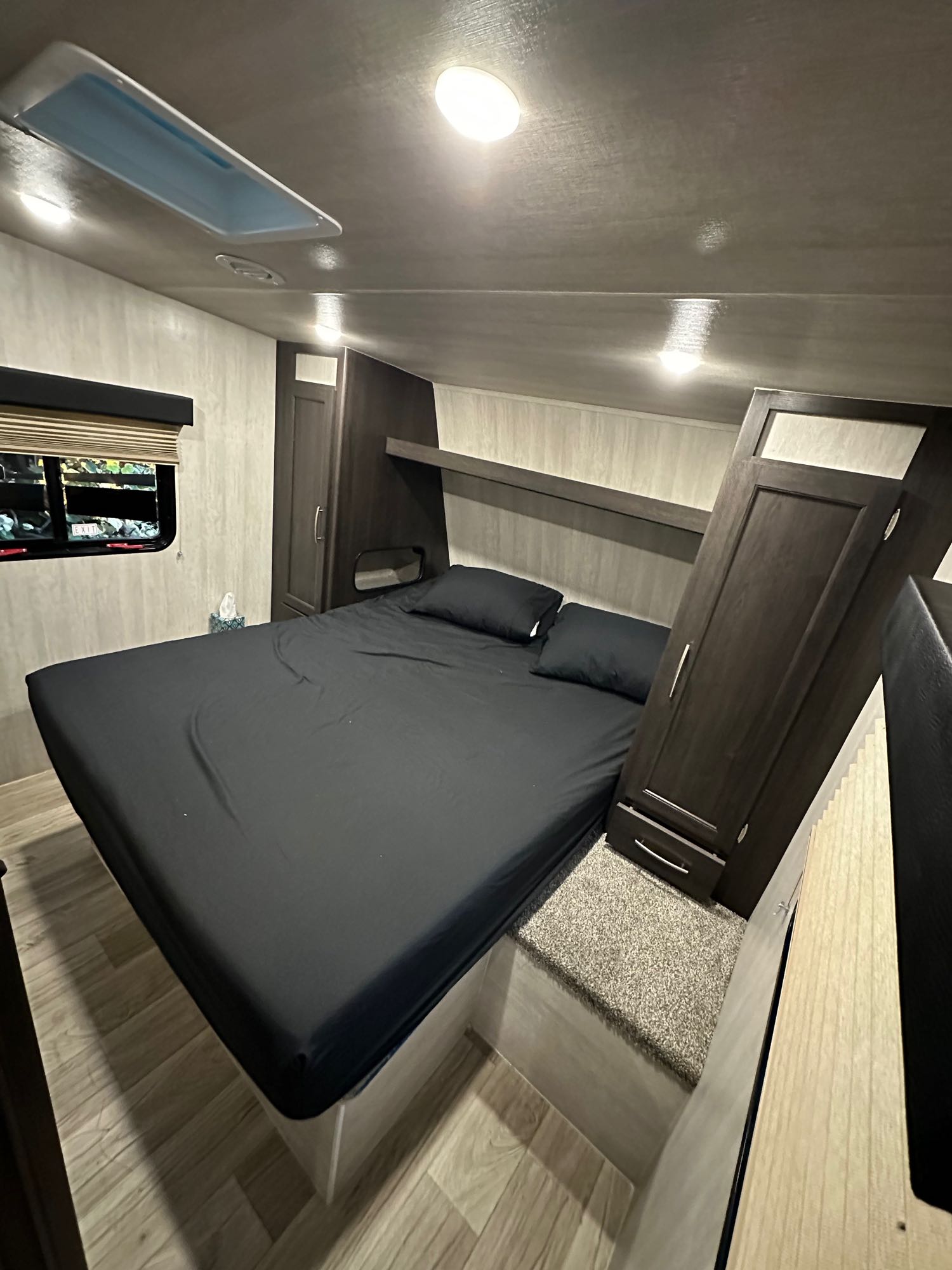 Cozy RV rental bedroom with a large bed, dark bedding, built-in storage, and a skylight overhead.. MGM limited by Genesis MFS275 2023