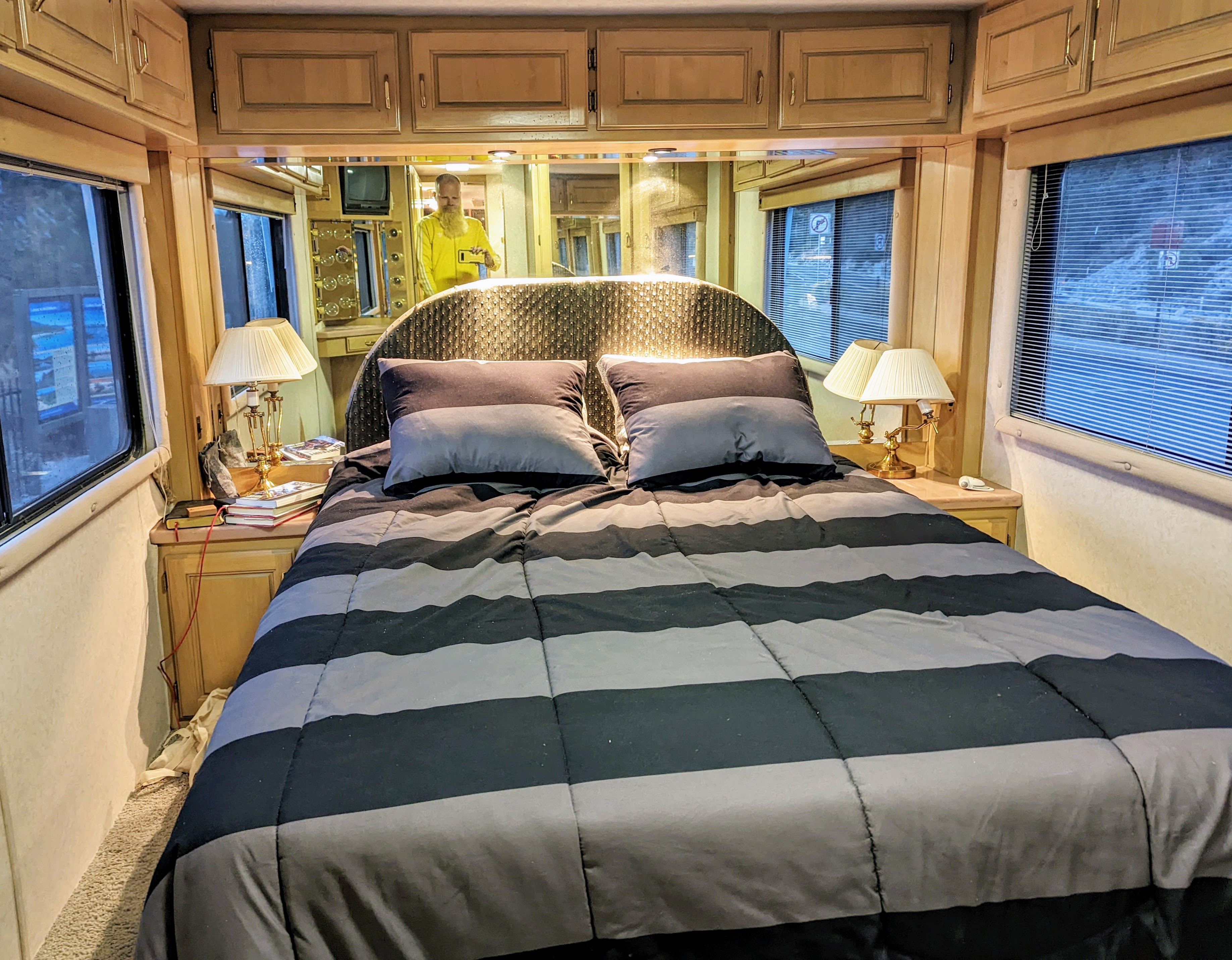 Inside an RV rental bedroom: a comfy bed with striped comforter, lamps, and overhead storage. Ready for travel!. Safari Continental 1993