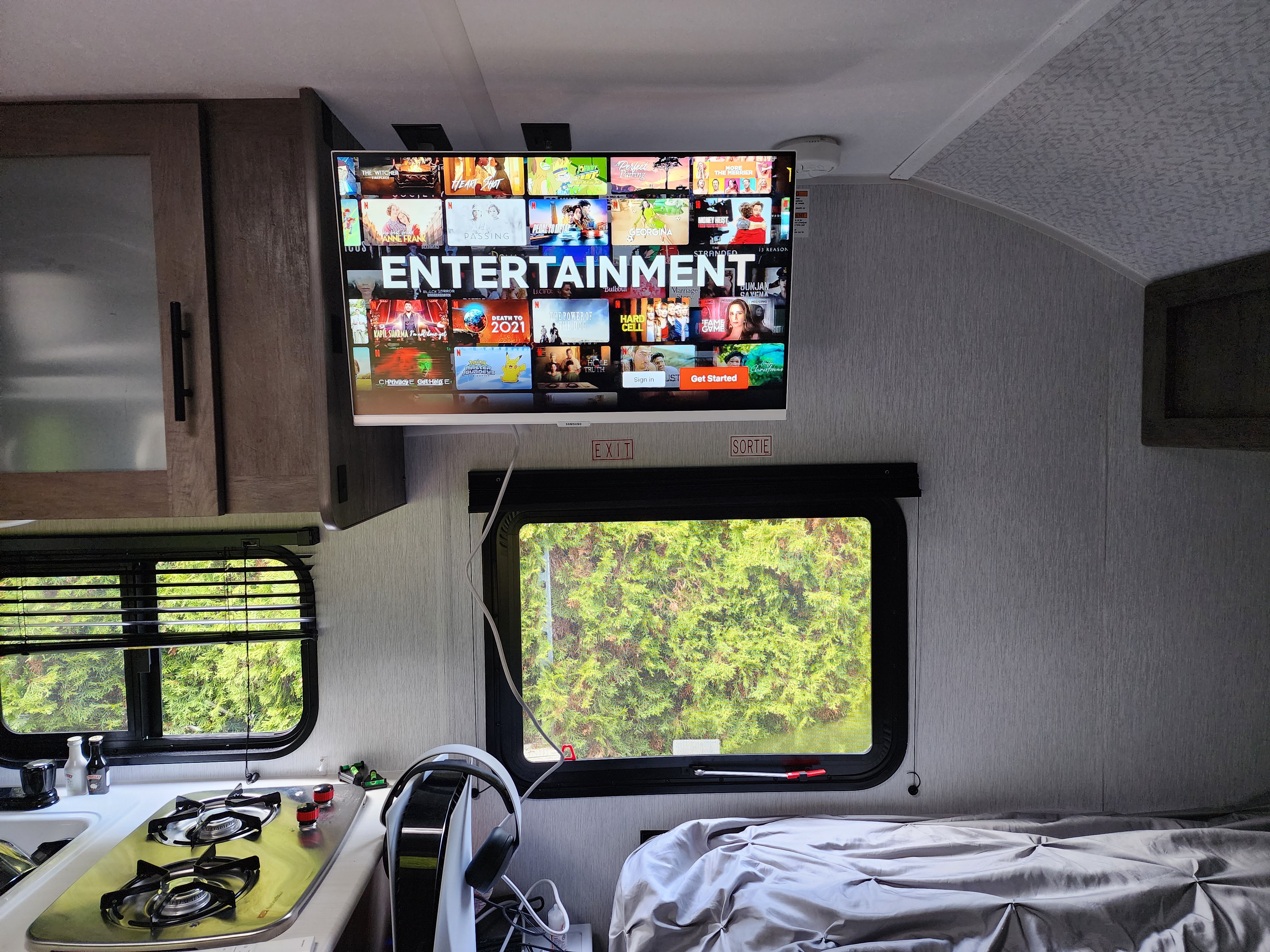Enjoy an RV rental's entertainment setup: a large TV with a streaming menu, adjacent kitchen, and cozy bed.. Forest River EVO 2022