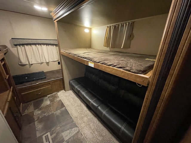 Spacious RV rental interior featuring comfortable bunk beds, a futon sofa, and storage for a cozy camping experience.. Crossroads RV Rezerve 2017