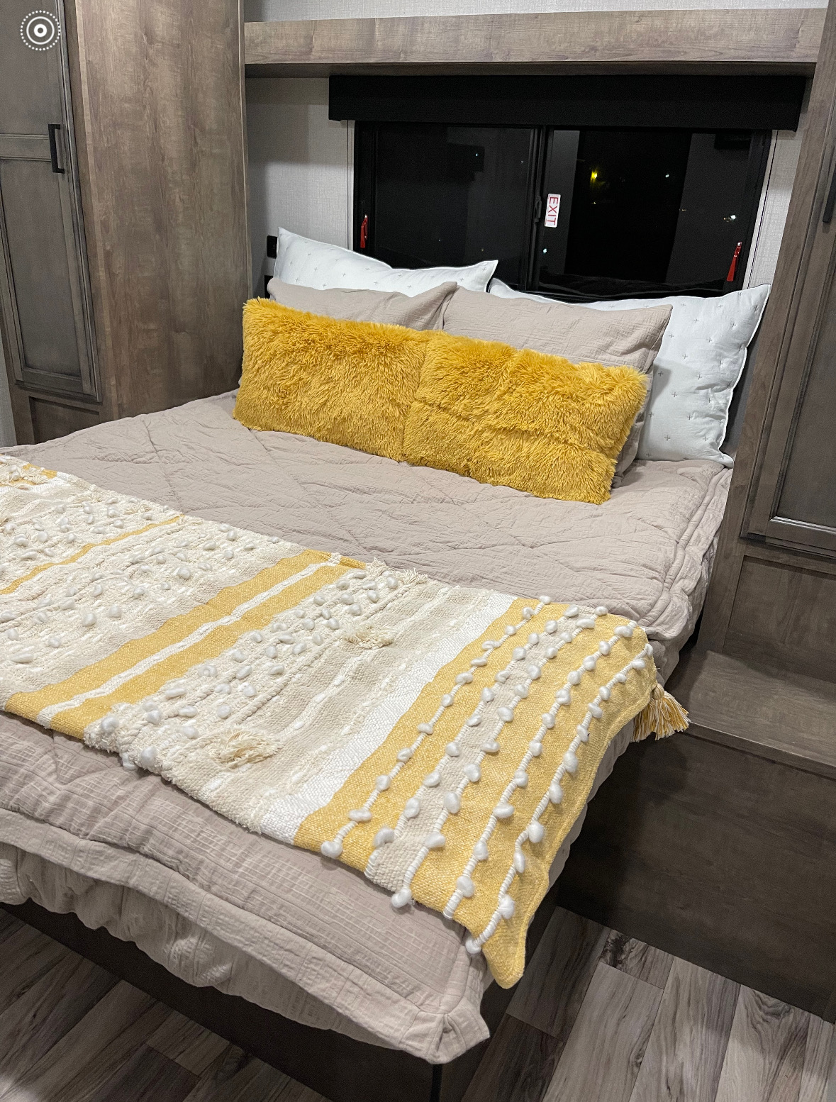 Warm RV rental bedroom features a bed with cozy bedding, bright yellow pillows, and a textured throw blanket.. Venture Rv Sporttrek 2021