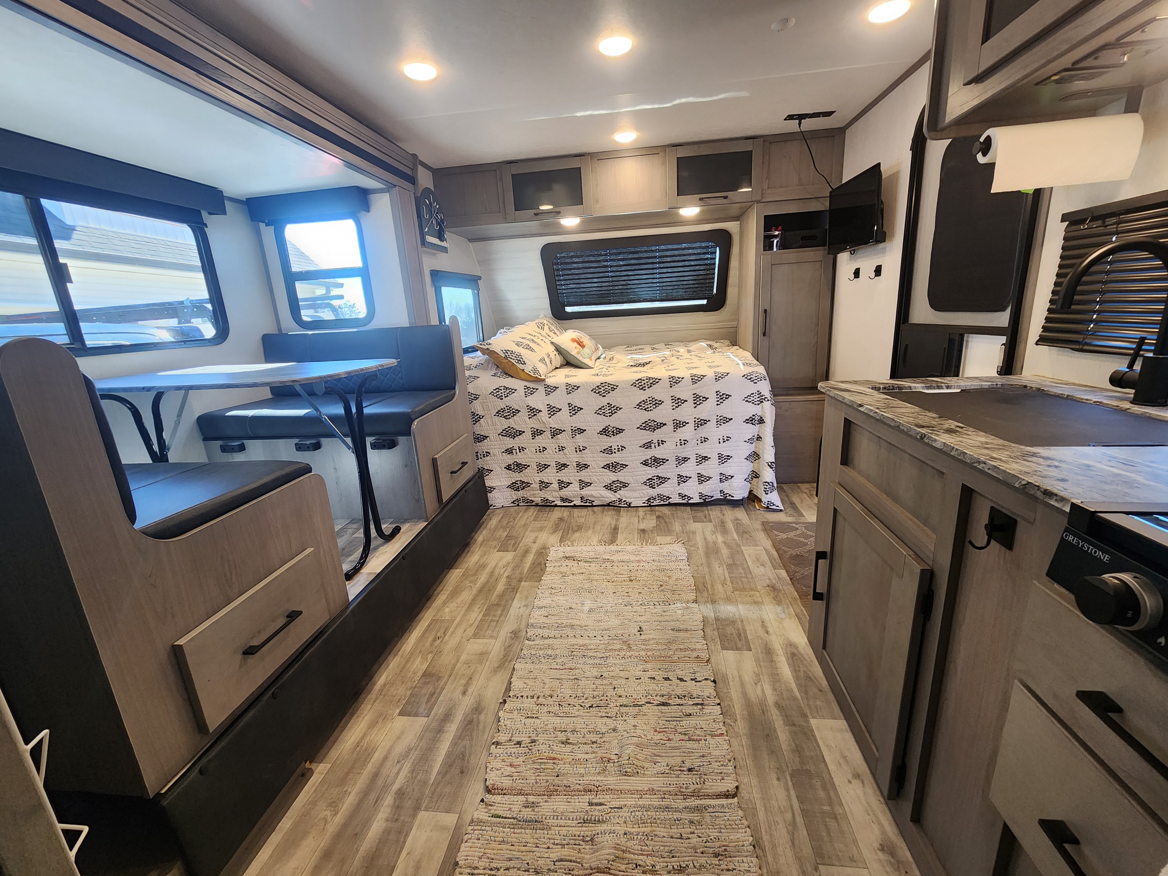 Bright, modern RV rental interior featuring a dinette, cozy bed, kitchen, and warm wood-look floors.. Dutchmen Kodiak Cub 2022