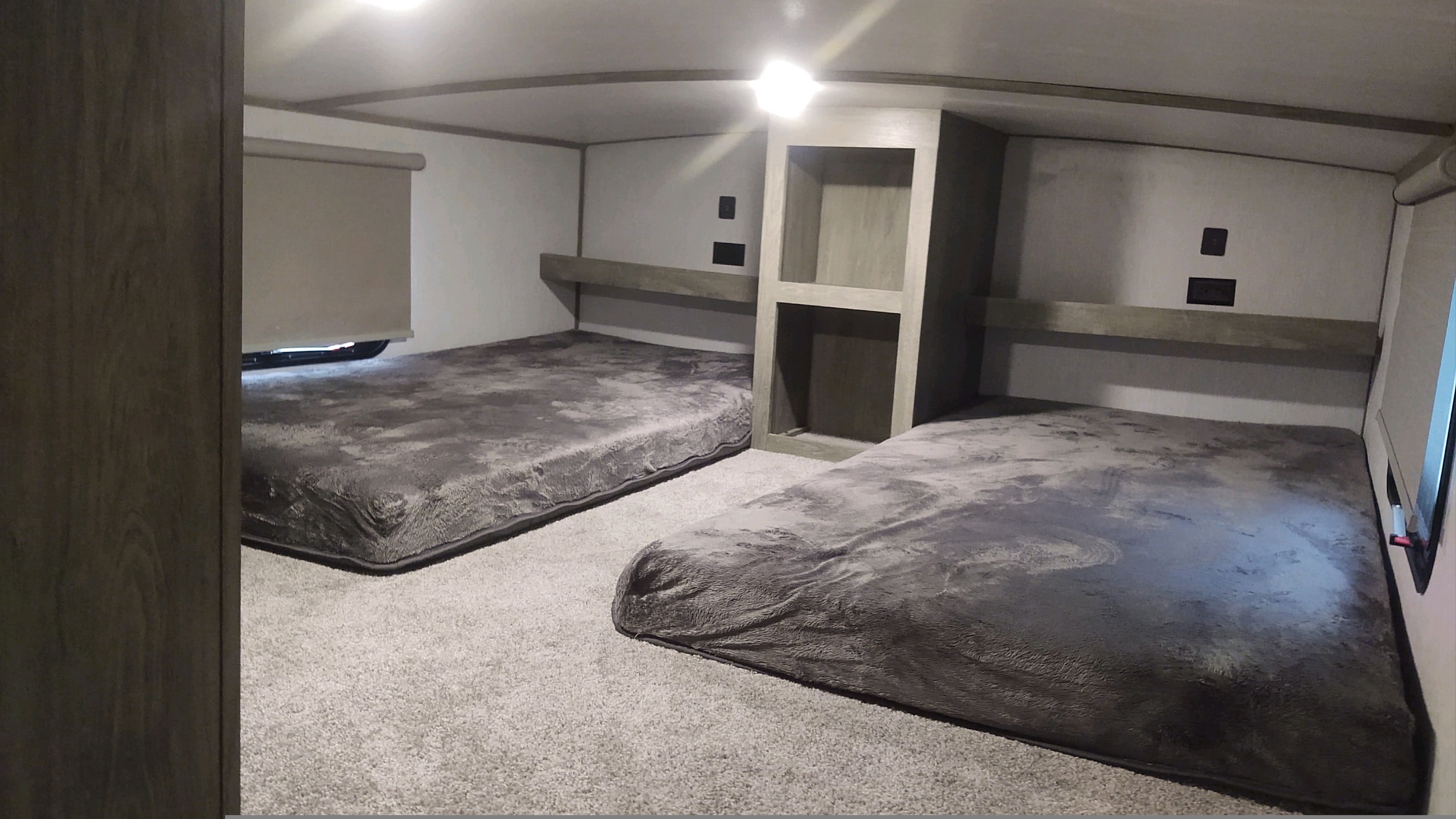 Cozy RV rental bunkhouse featuring two soft grey bunk beds, built-in storage, outlets, and plush carpeting for comfortable travel.. Forest River Salem Hemisphere 2022