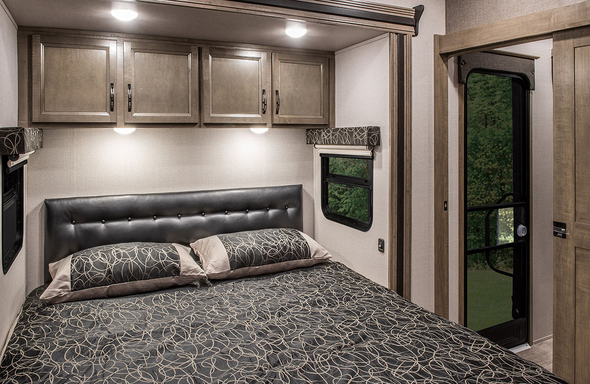 Comfortable RV rental bedroom with spacious bed, storage, and windows showcasing nature.. K-Z Manufacturing Durango 2017