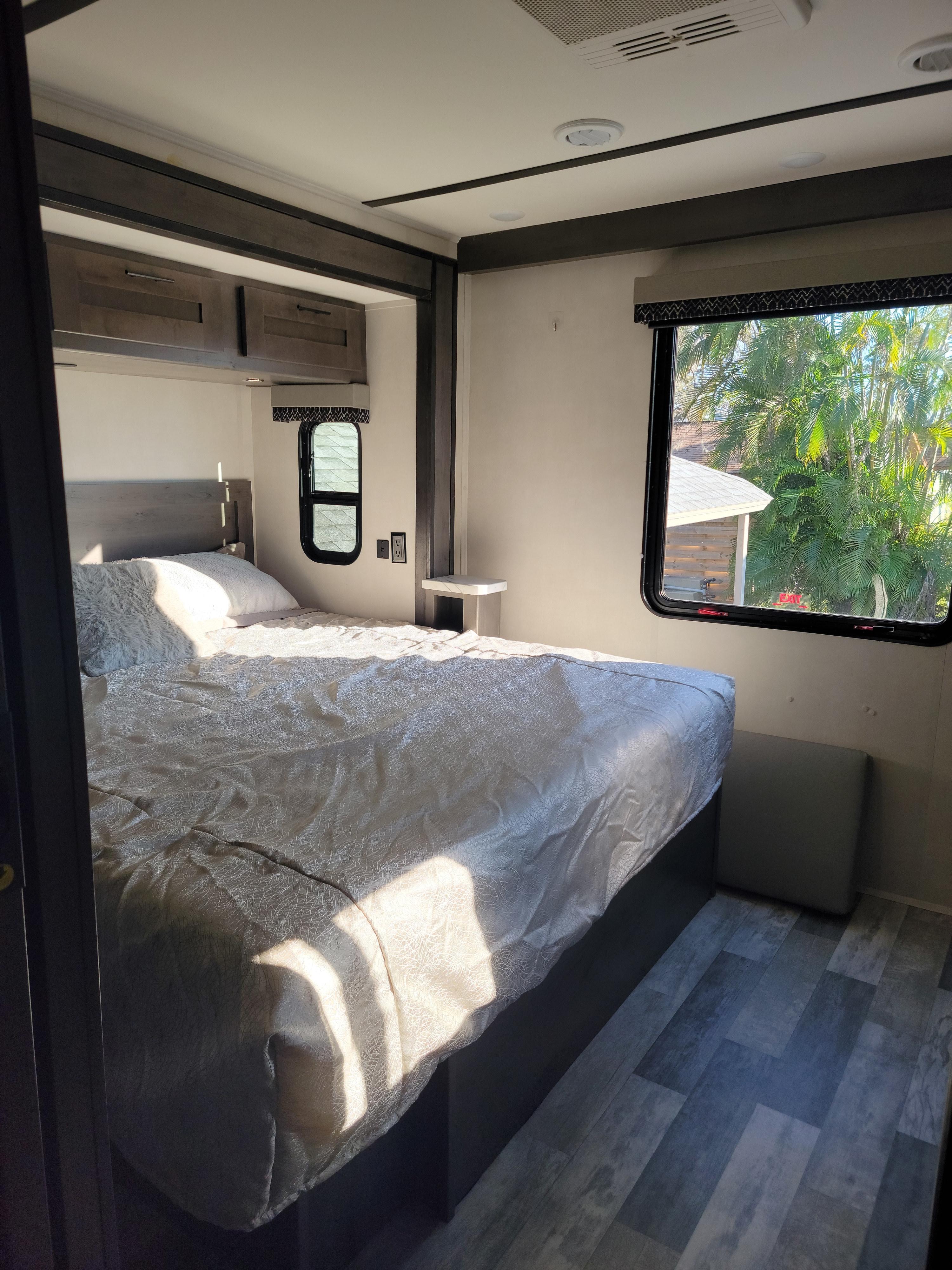 Bright and inviting RV rental bedroom. Features a comfy bed, overhead cabinets, and large window views.. FR3 FR3 Motorhome 2022