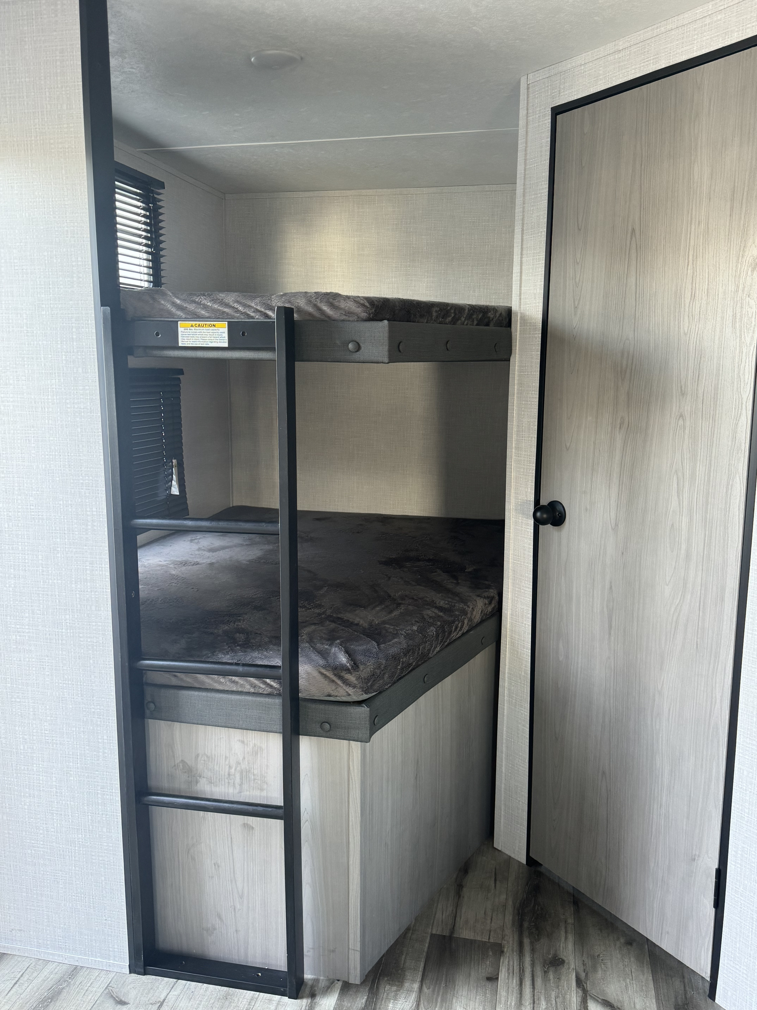 RV rental bunk beds. Modern camper interior with two bunks, ladder & windows.. Dutchmen Coleman Light 2023
